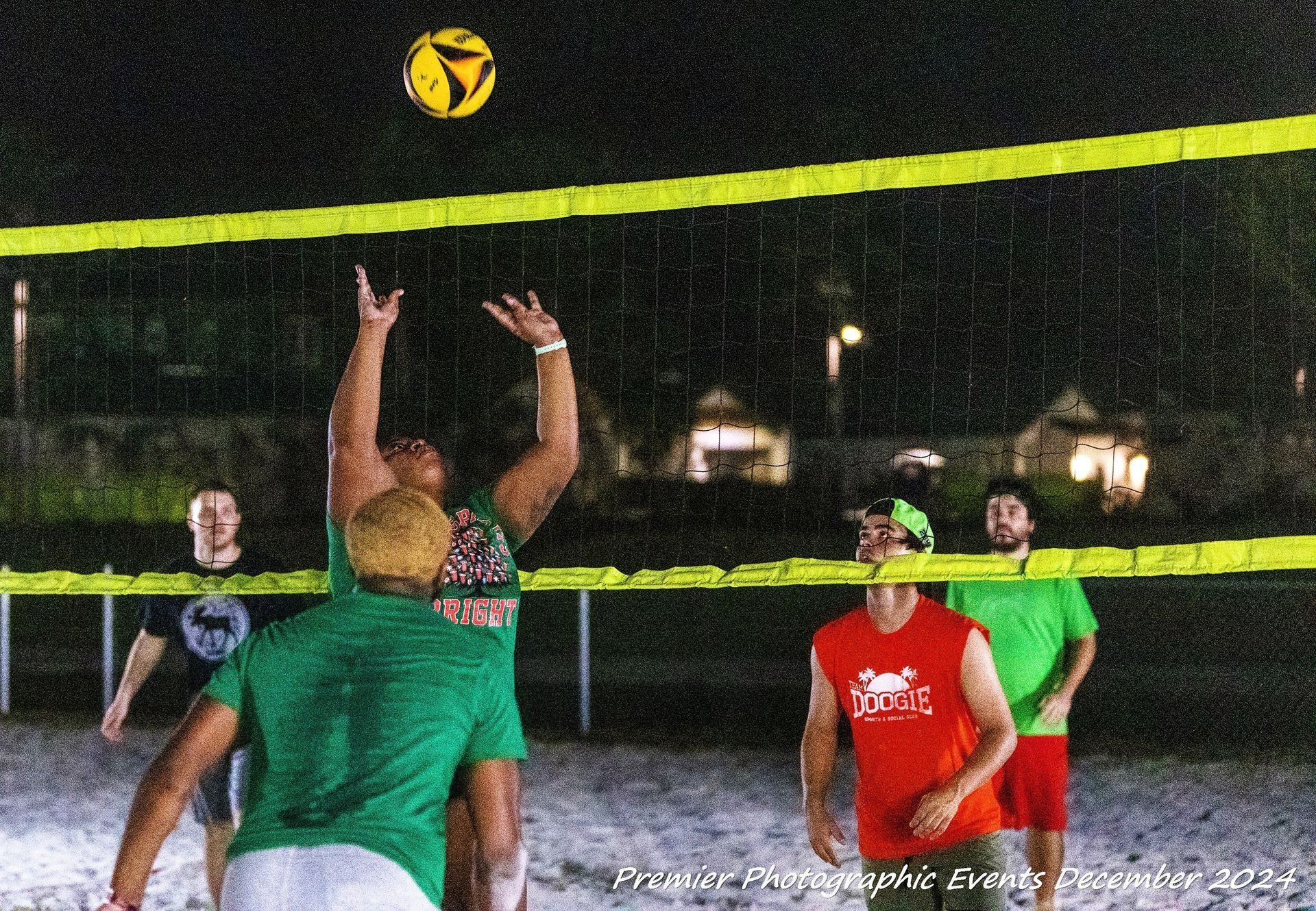 A group of people are playing volleyball on a beach at night.