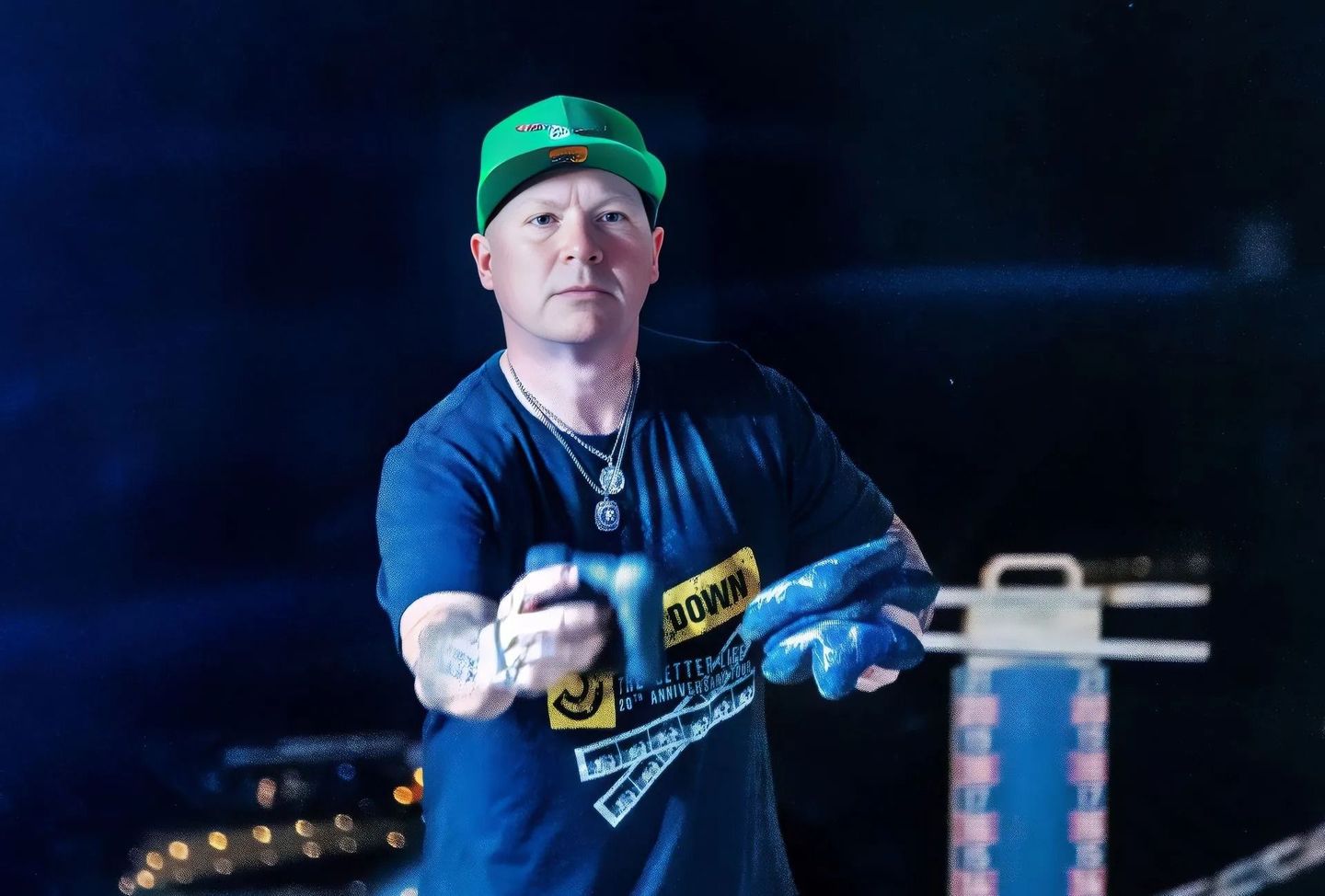 A man in a blue shirt and green hat is holding a blue object.