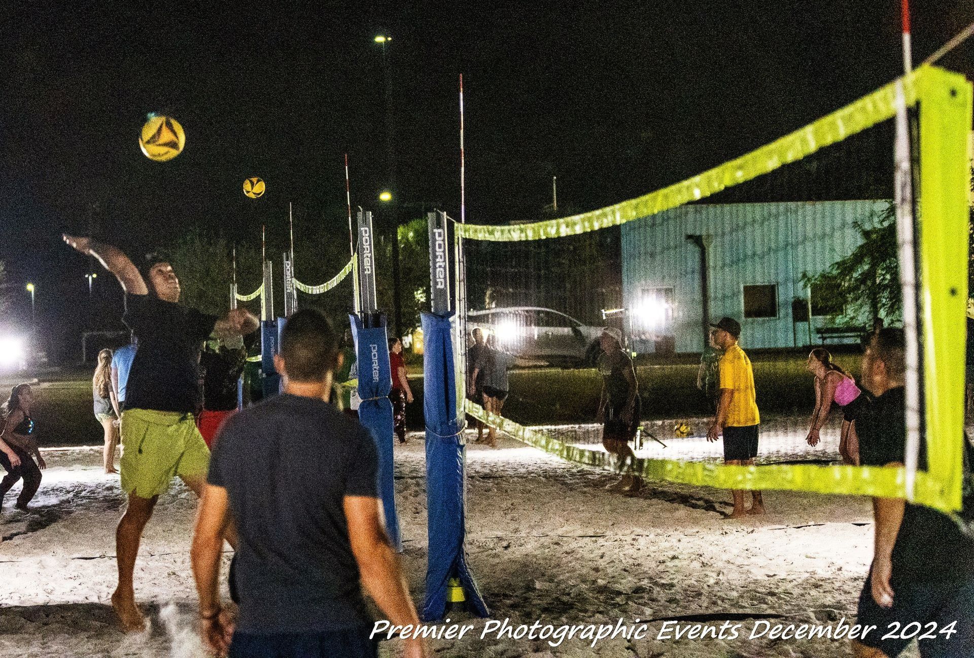 A group of people are playing volleyball on a beach at night.