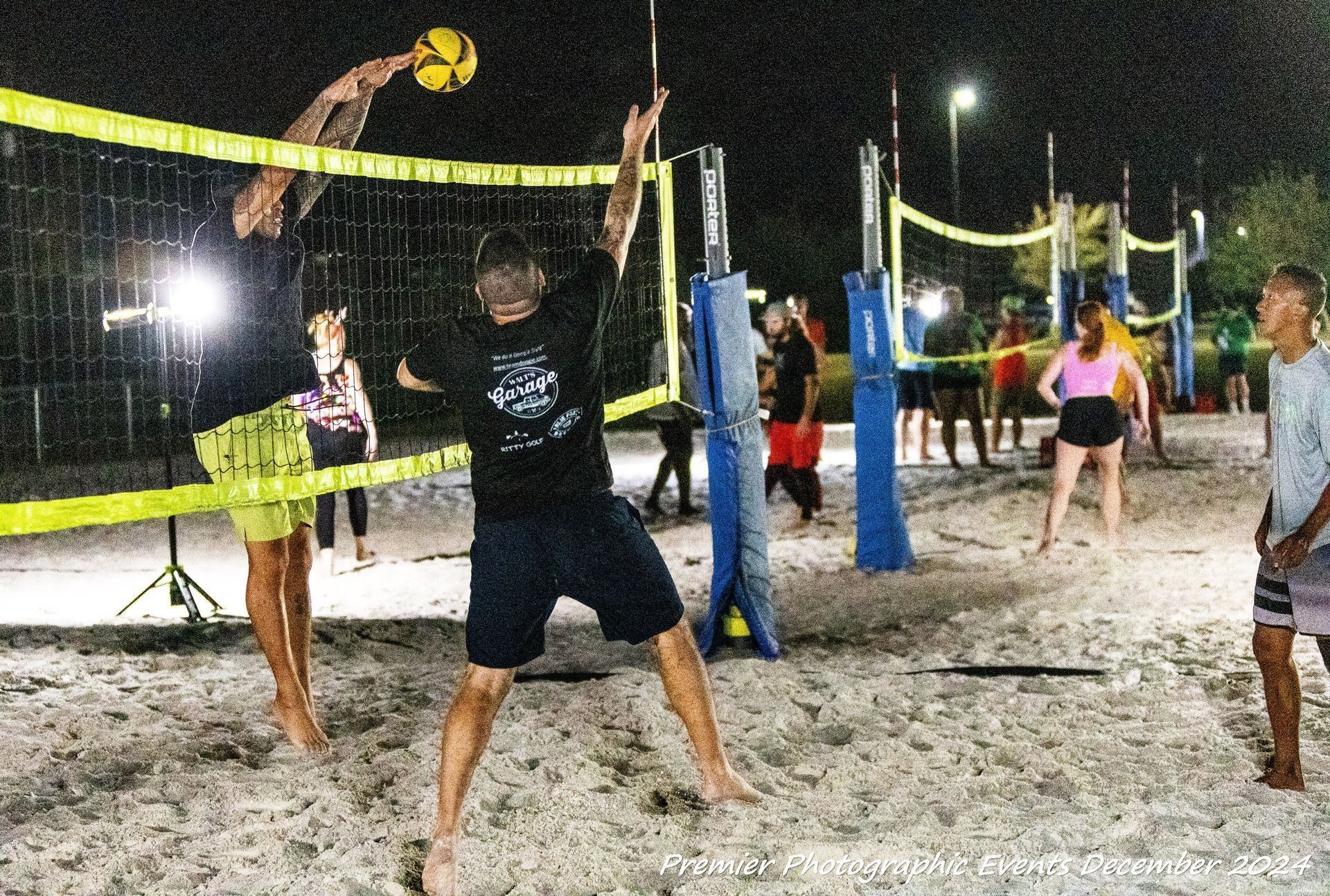 A group of people are playing volleyball on a beach at night.