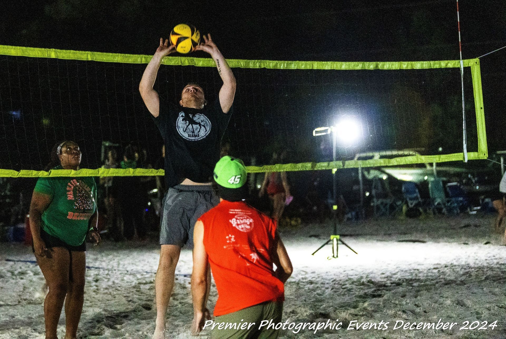 A group of people are playing volleyball on a beach at night