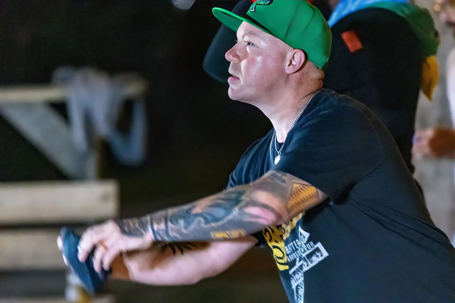A man wearing a green hat and a black shirt is throwing a frisbee.