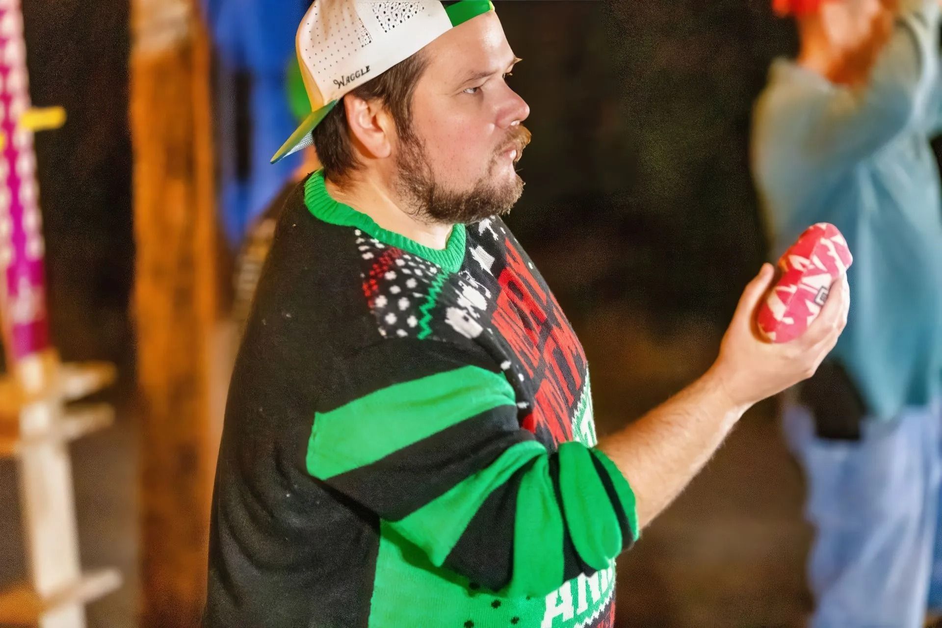 A man in a green sweater is holding a can of soda.