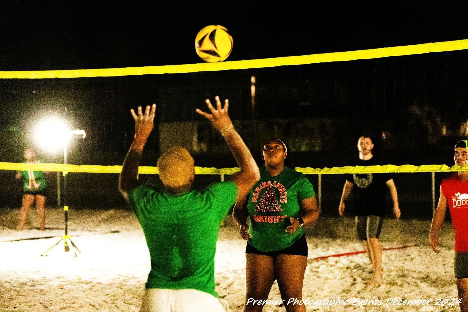 A group of people are playing volleyball on a beach at night
