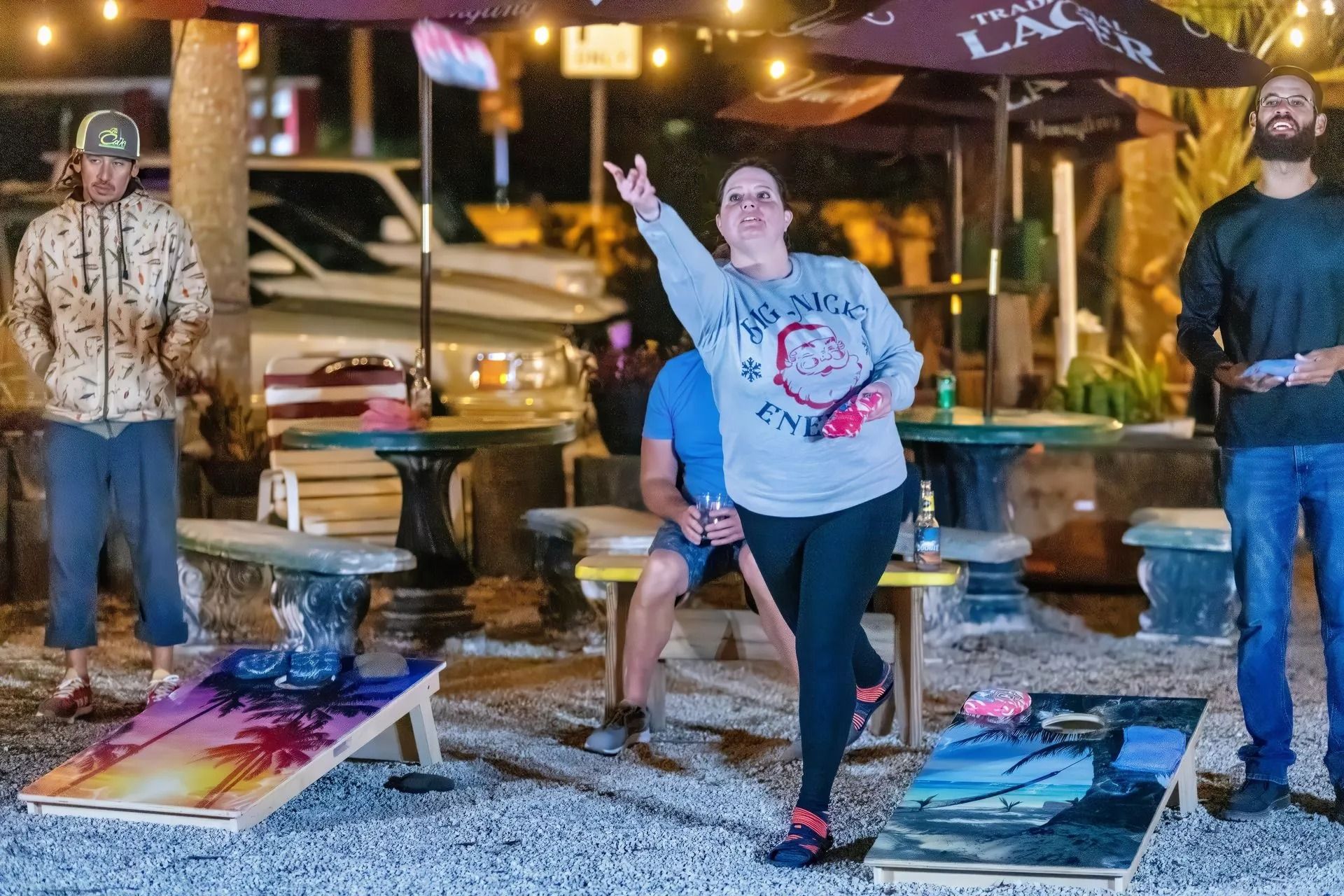 A group of people are playing a game of cornhole outside.