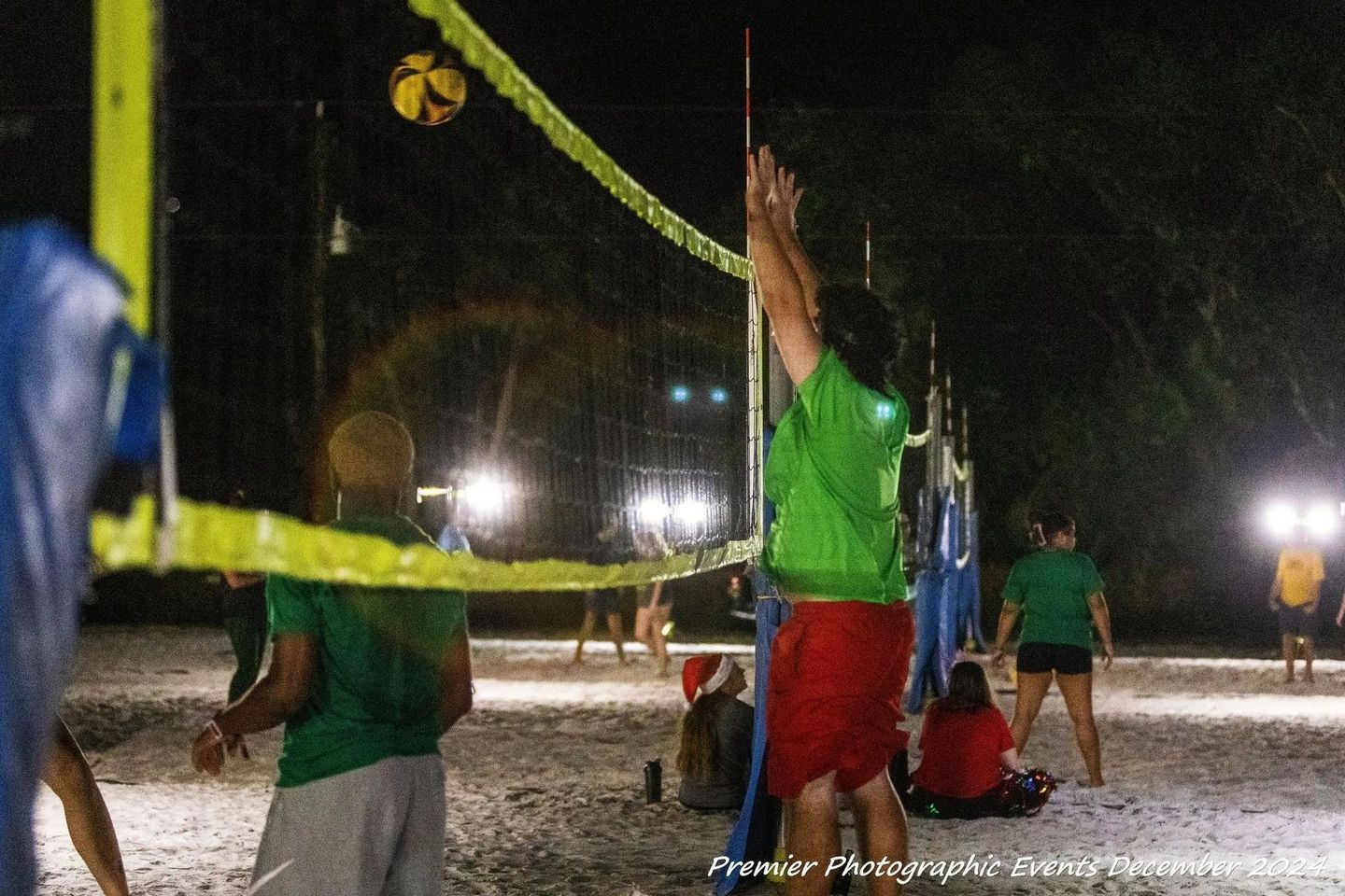 A group of people are playing volleyball on a beach at night