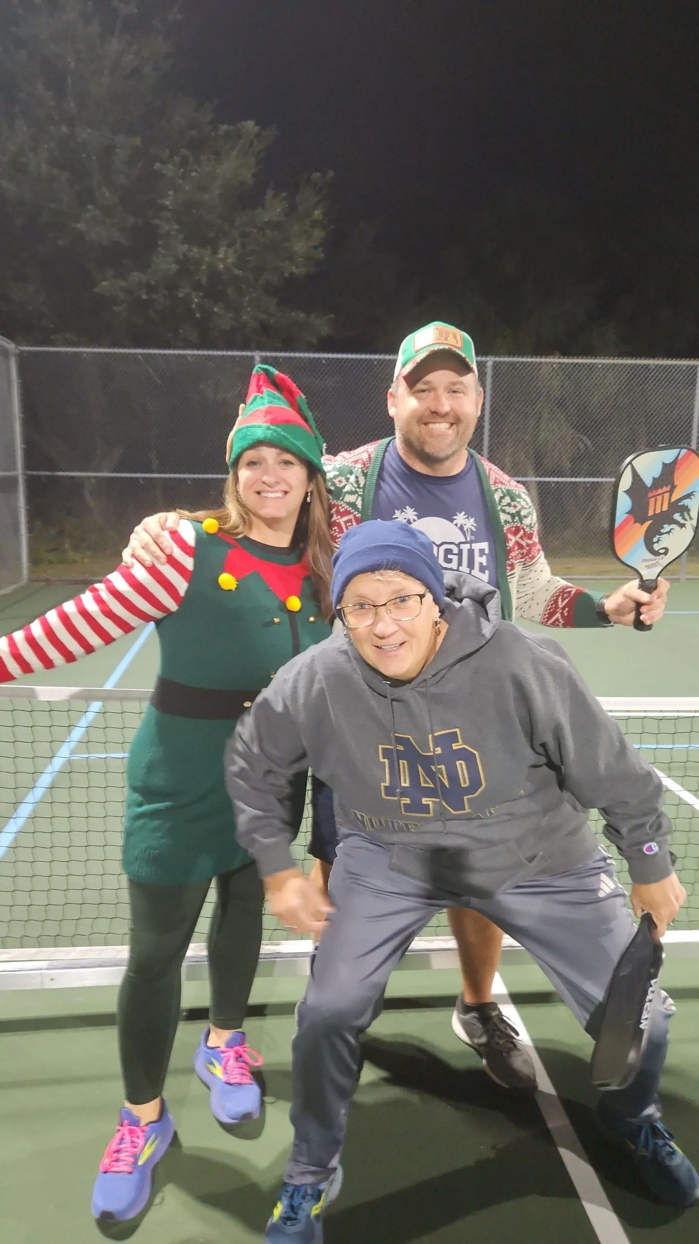A group of people are posing for a picture on a tennis court.