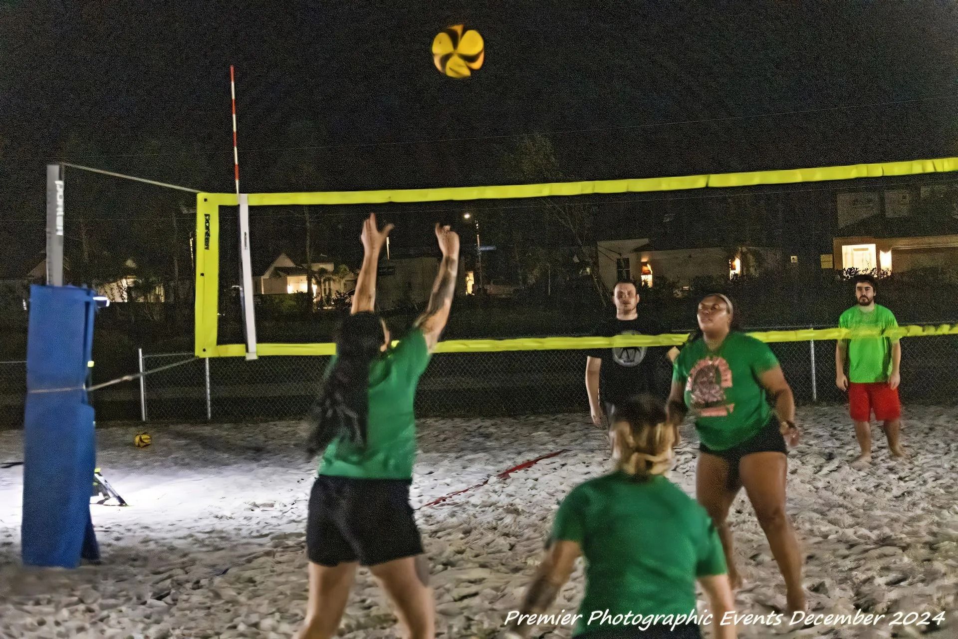 A group of people are playing volleyball on a beach at night
