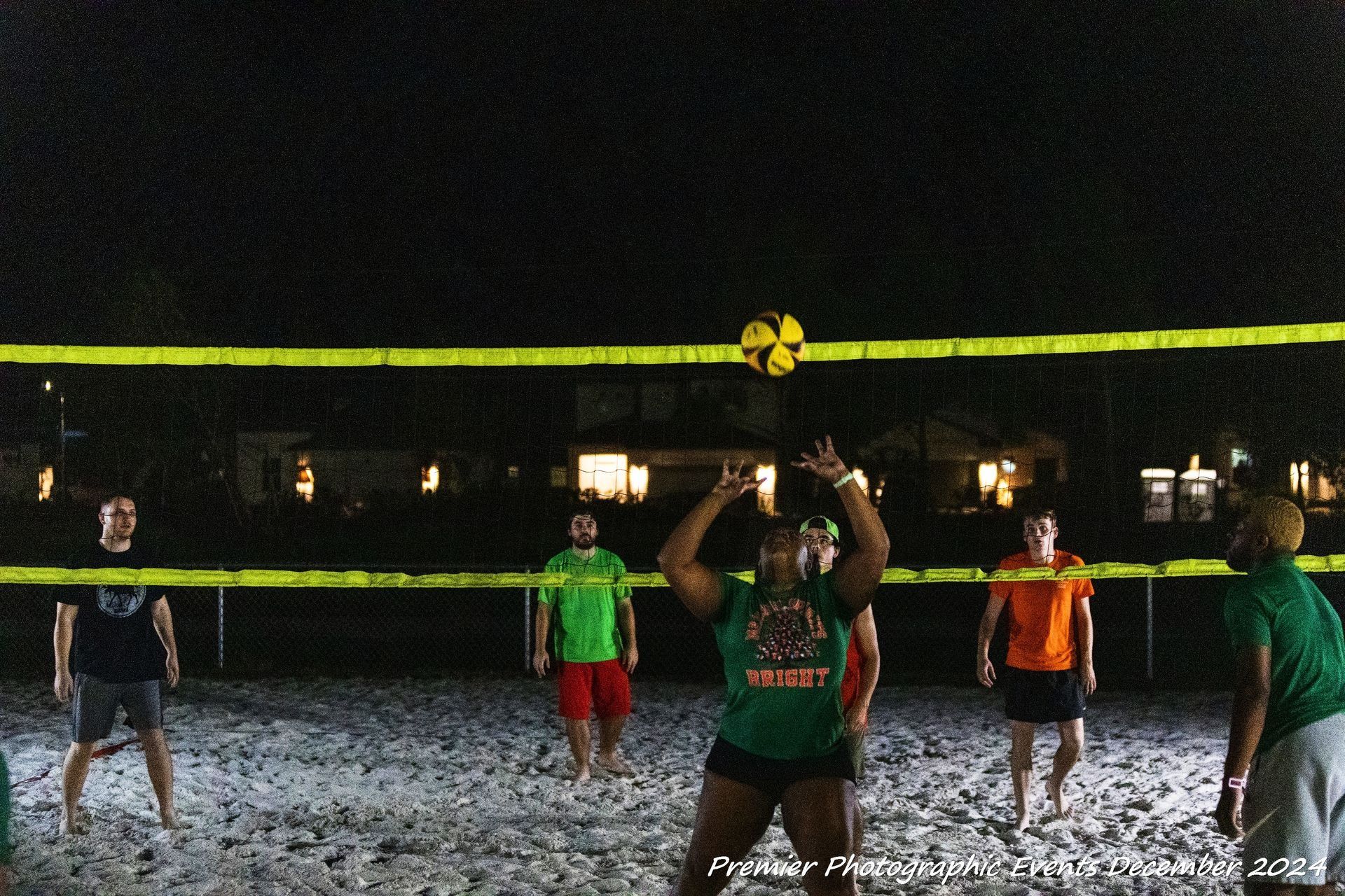A group of people are playing volleyball on a beach at night