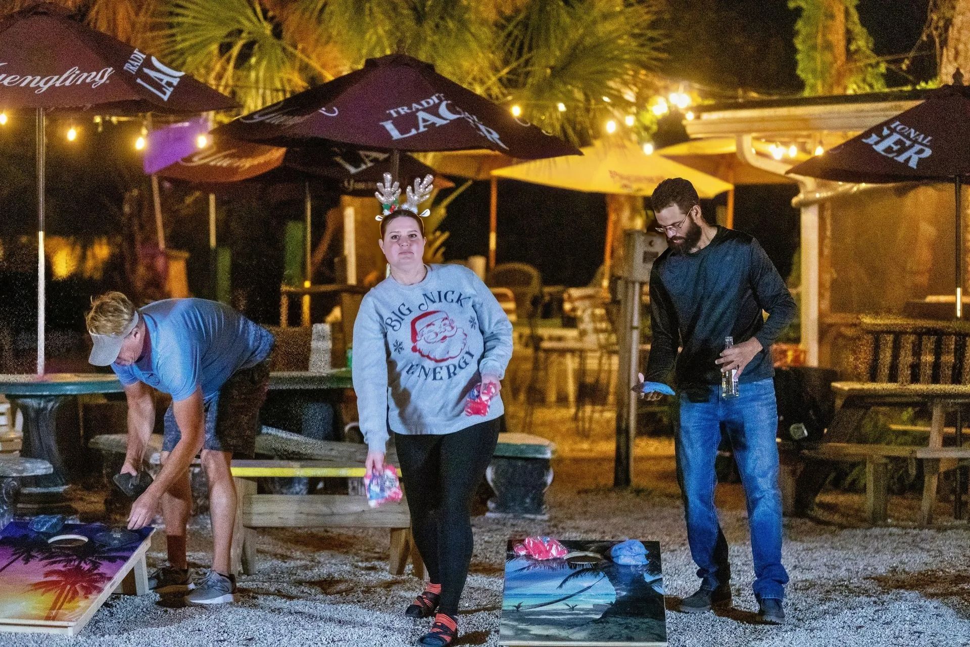 A group of people are playing a game of cornhole outside of a restaurant.