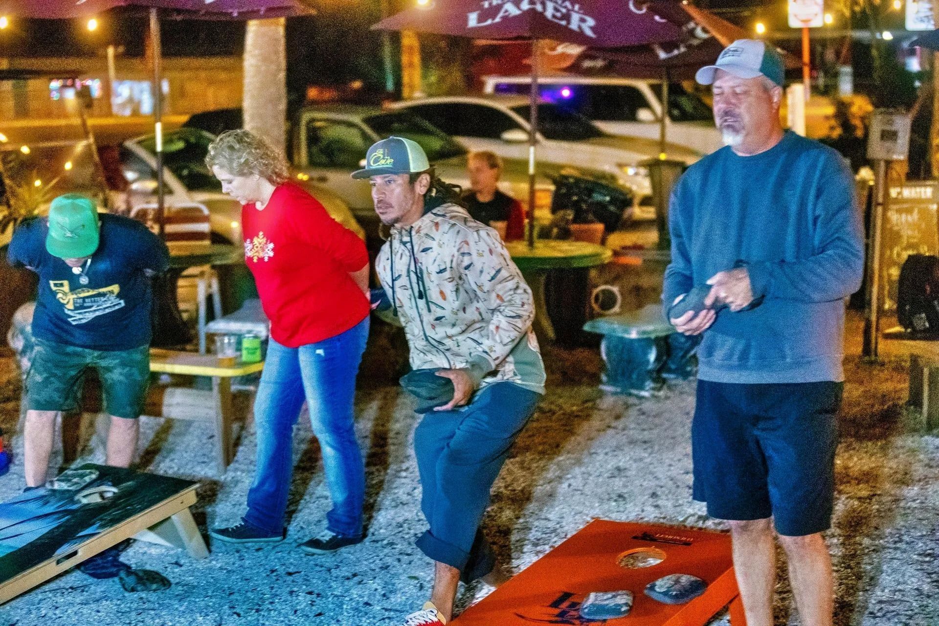A group of people are playing a game of cornhole outside.