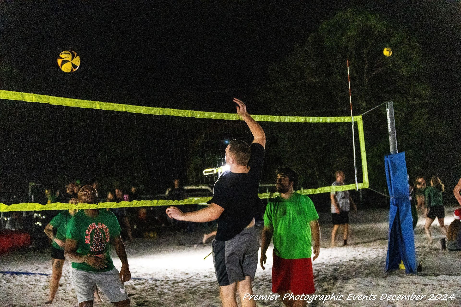 A group of people are playing volleyball on a beach at night