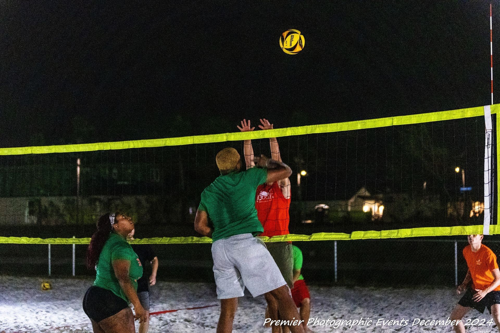 A group of people are playing volleyball on a beach at night