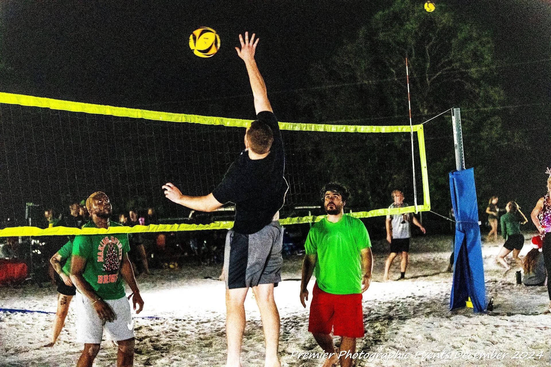 A group of people are playing volleyball on a beach at night.