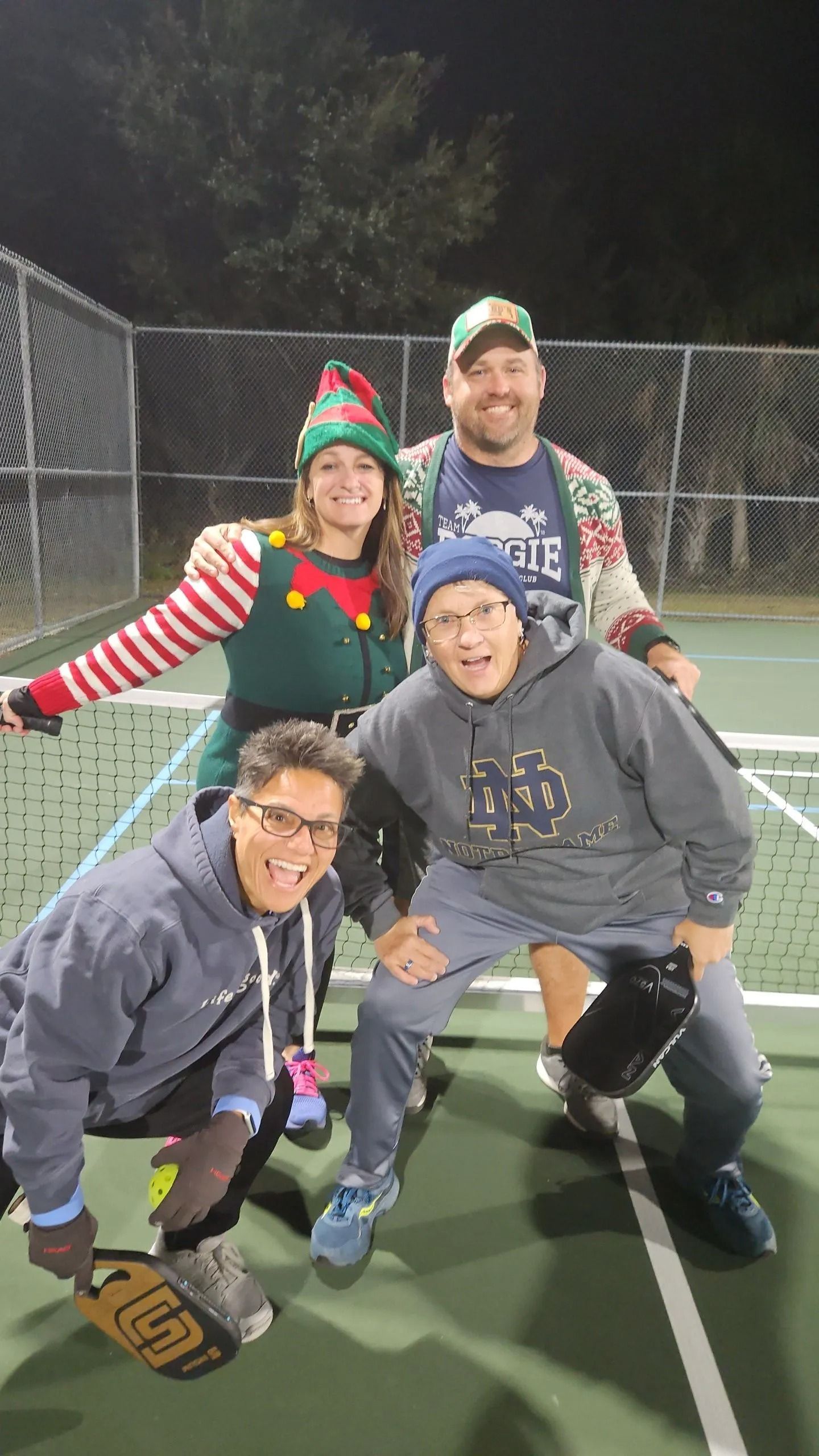 A group of people are posing for a picture on a tennis court.