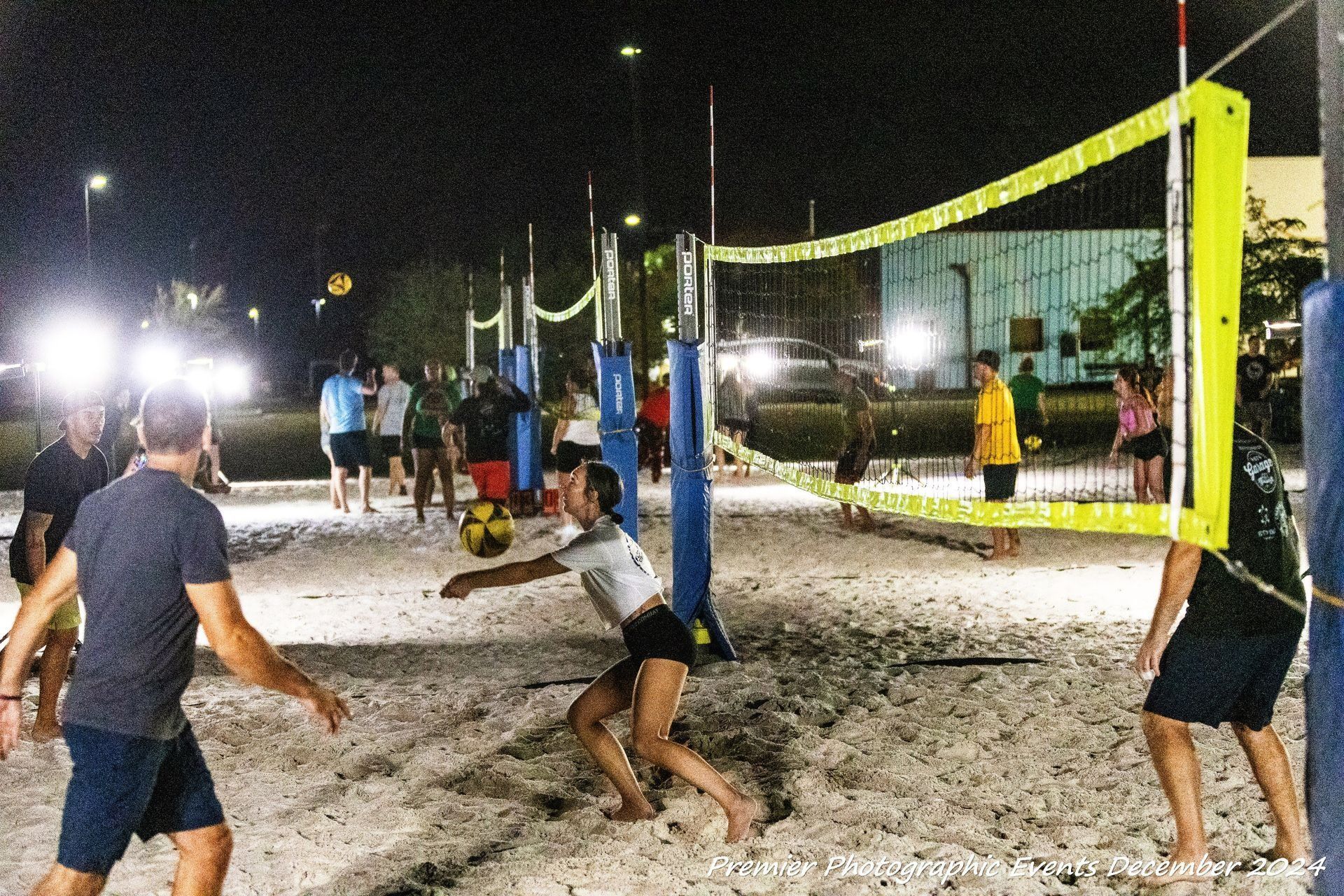 A group of people are playing volleyball on a beach at night.