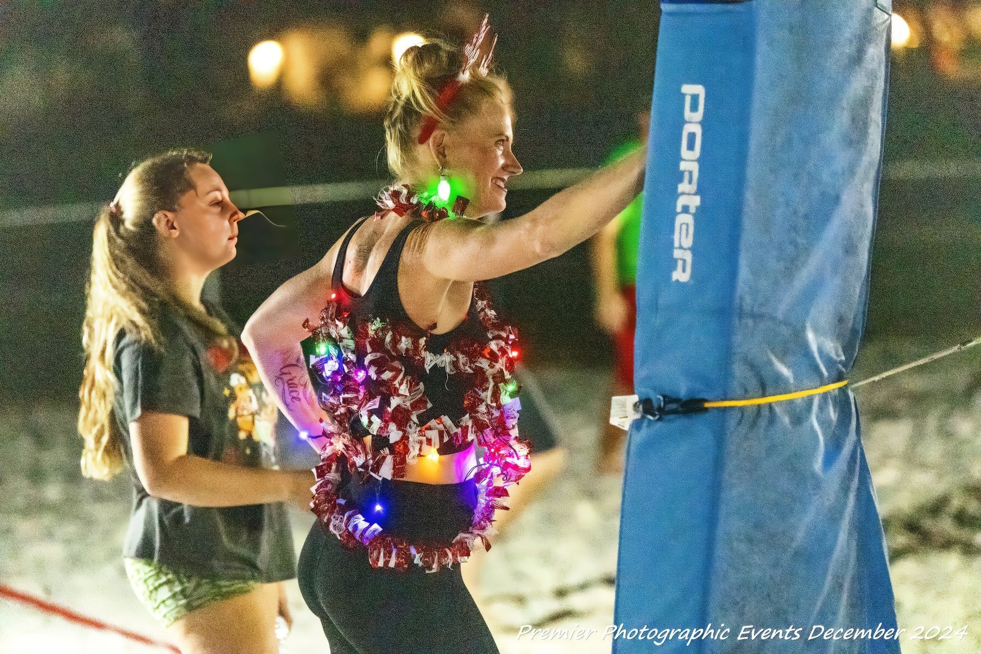 A woman is standing next to a blue porter volleyball net.