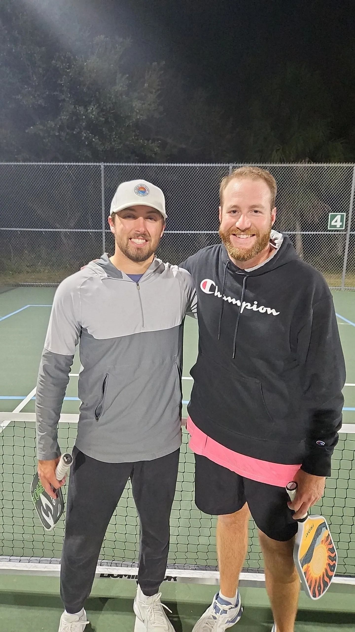 Two men are posing for a picture on a tennis court.