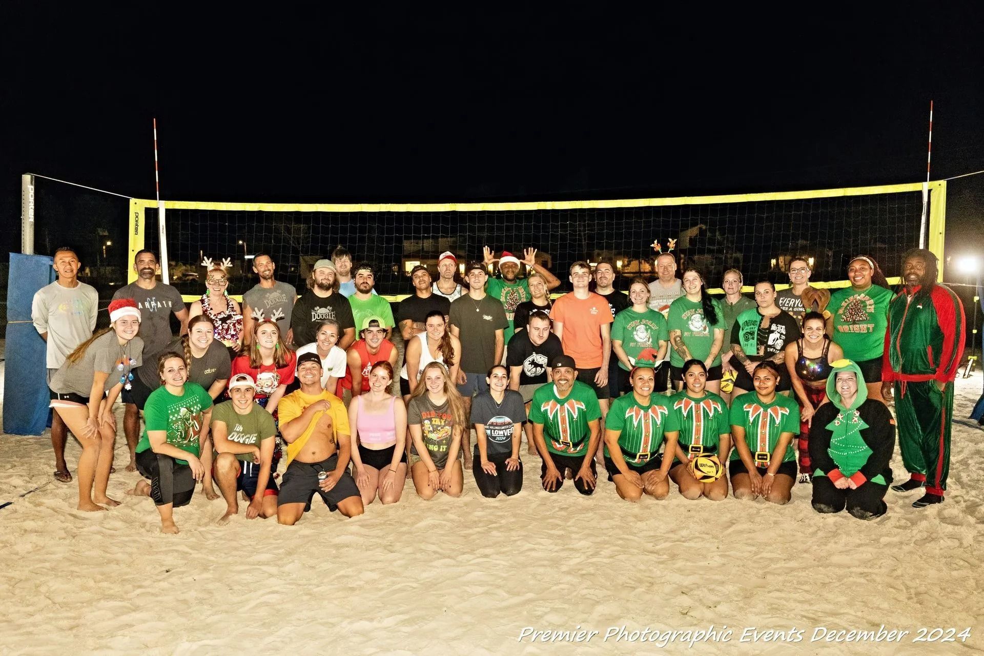 A group of people are posing for a picture in front of a volleyball net.