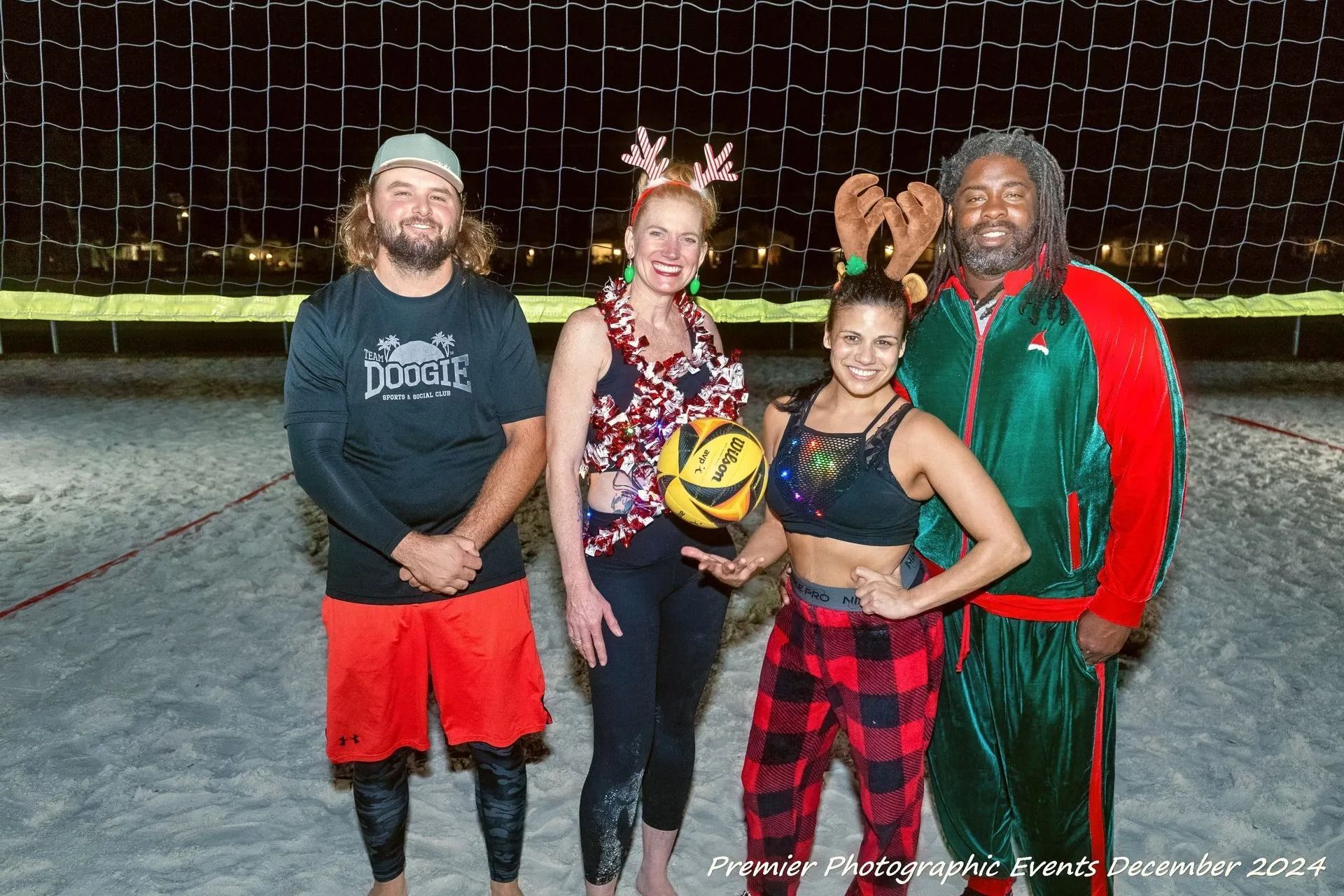 A group of people are posing for a picture in front of a volleyball net.