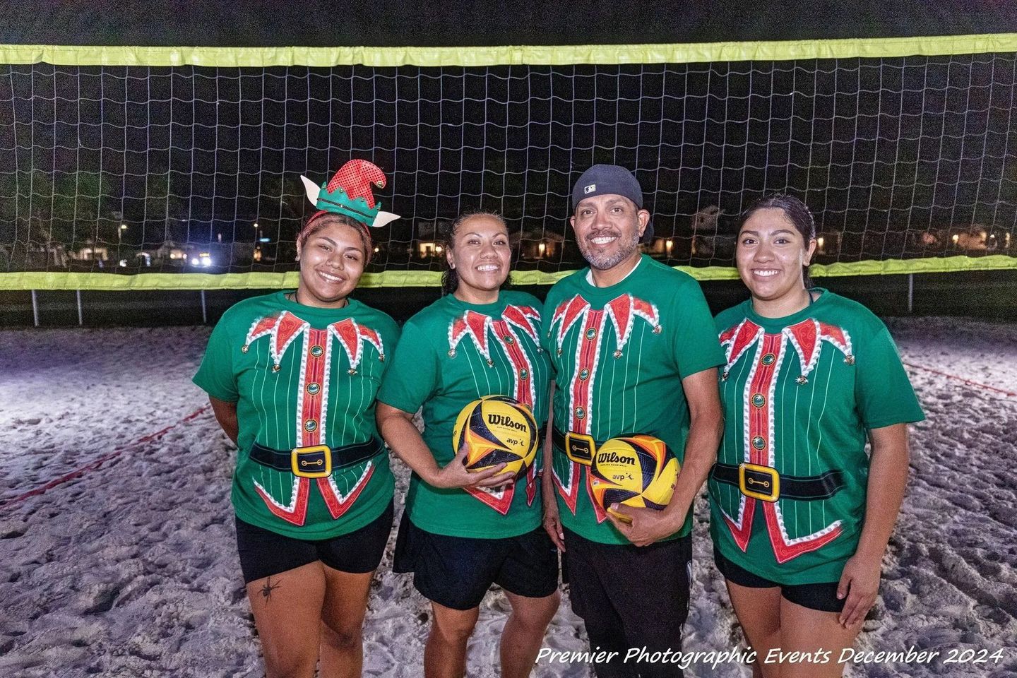 A group of people are posing for a picture in front of a volleyball net.