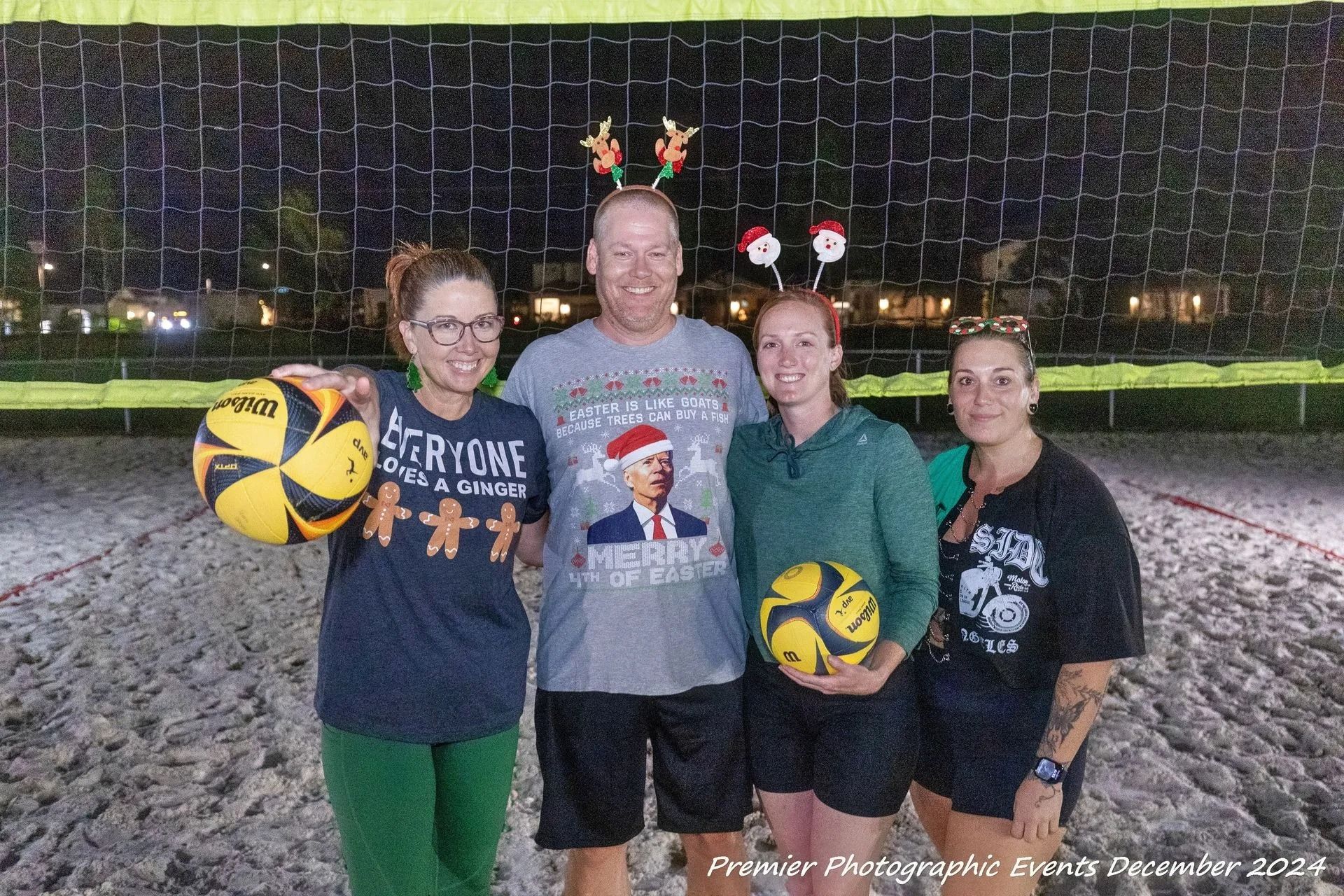 A group of people standing next to each other on a beach holding volleyballs.