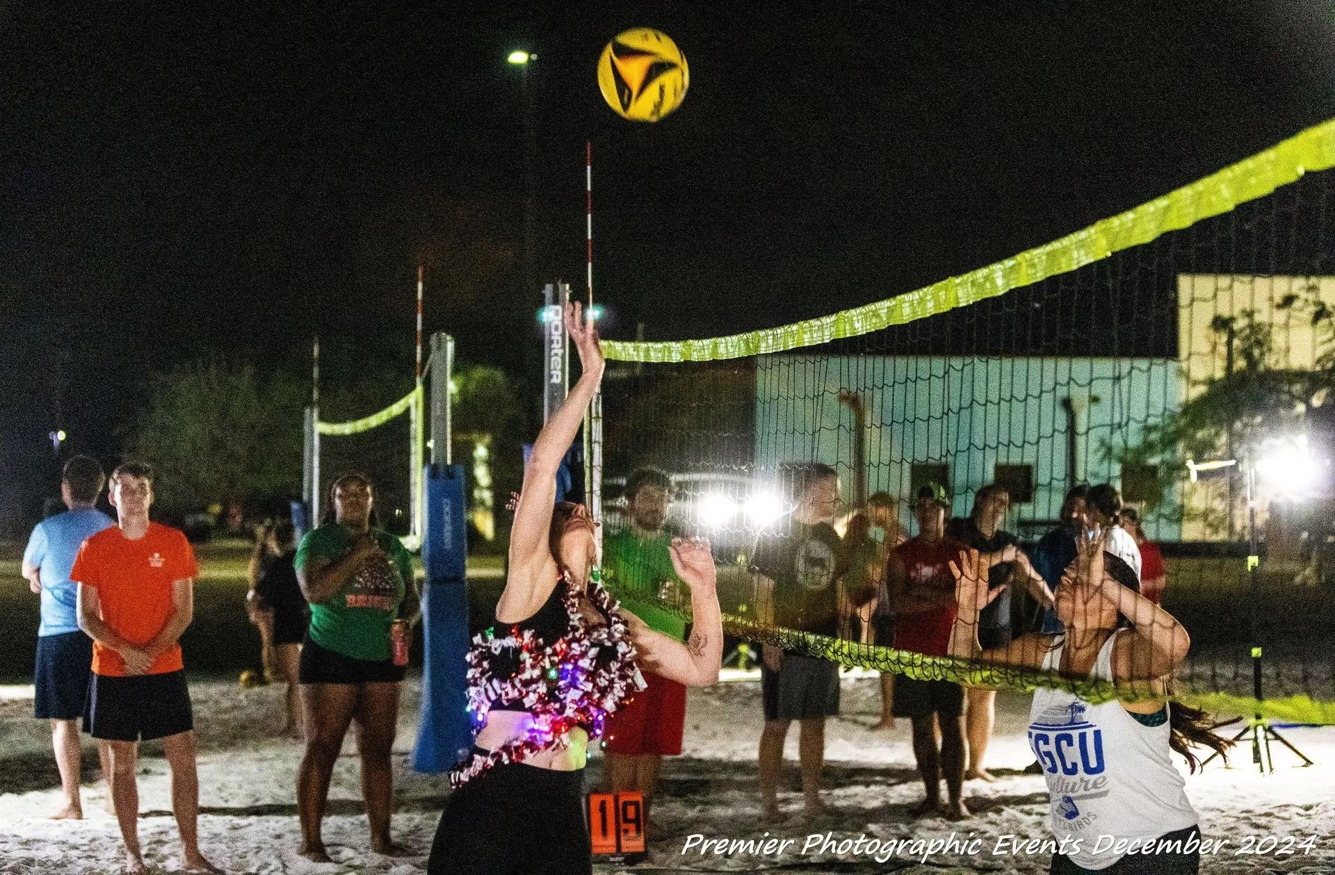 A group of people are playing volleyball on a beach at night