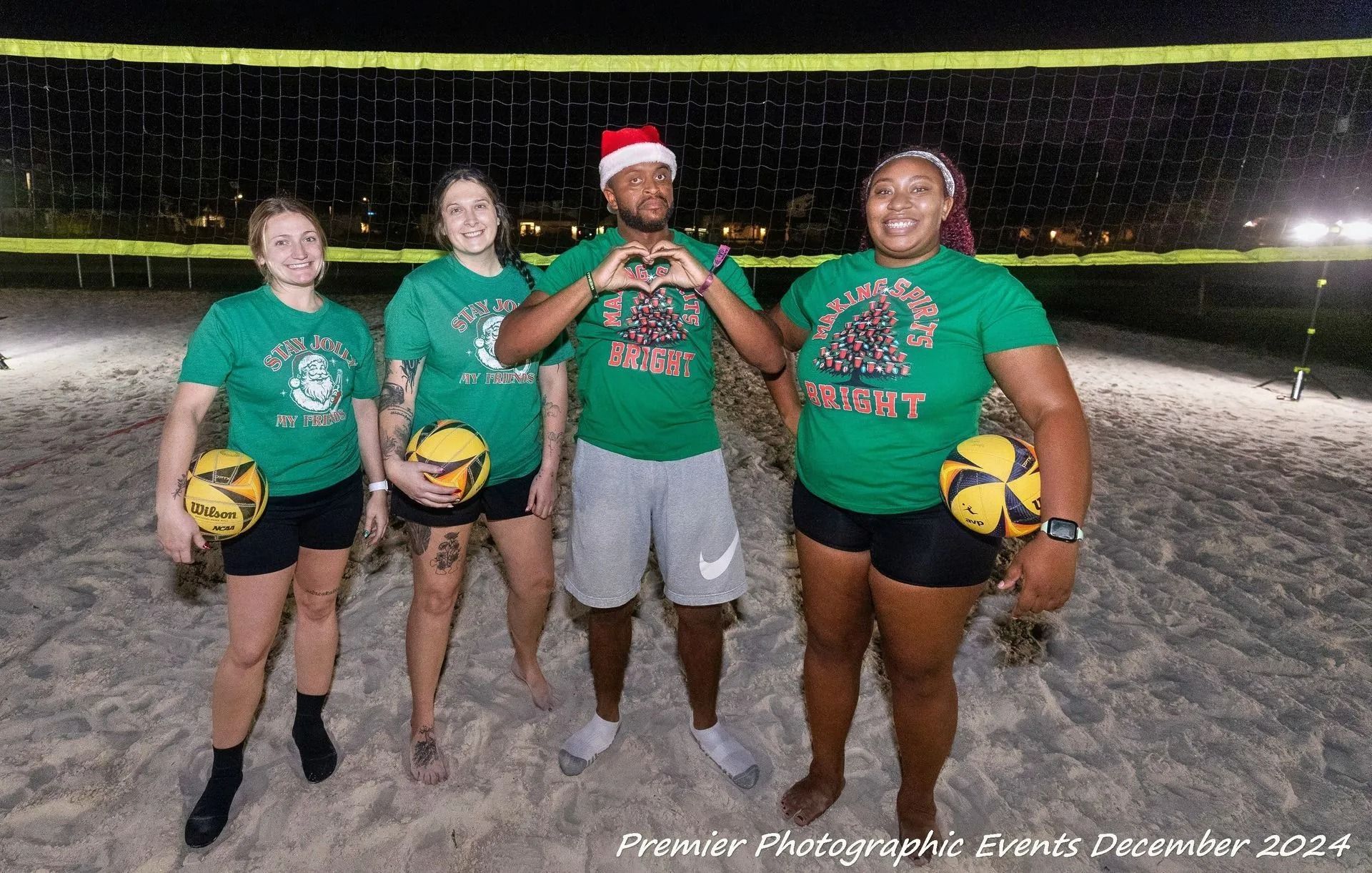 A group of people standing on a beach holding volleyballs.