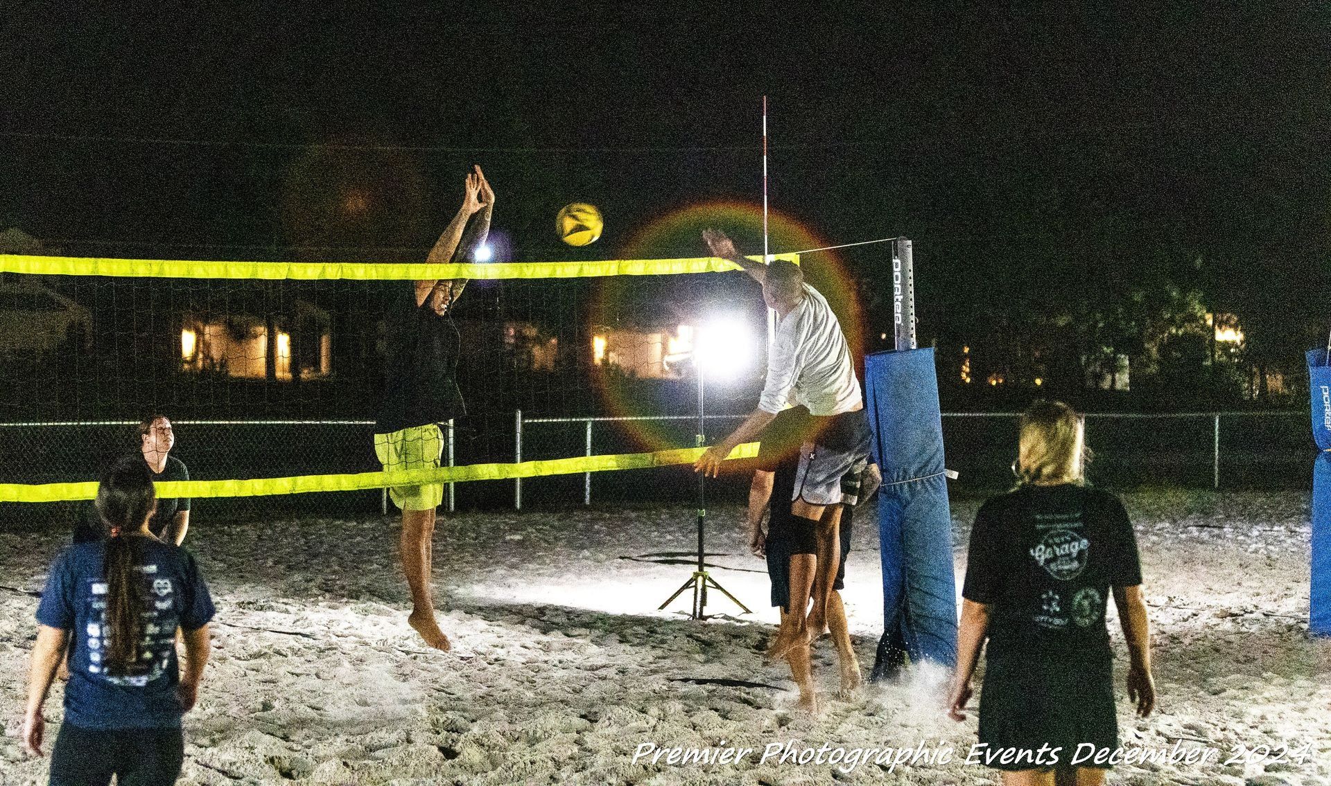 A group of people are playing volleyball on a beach at night