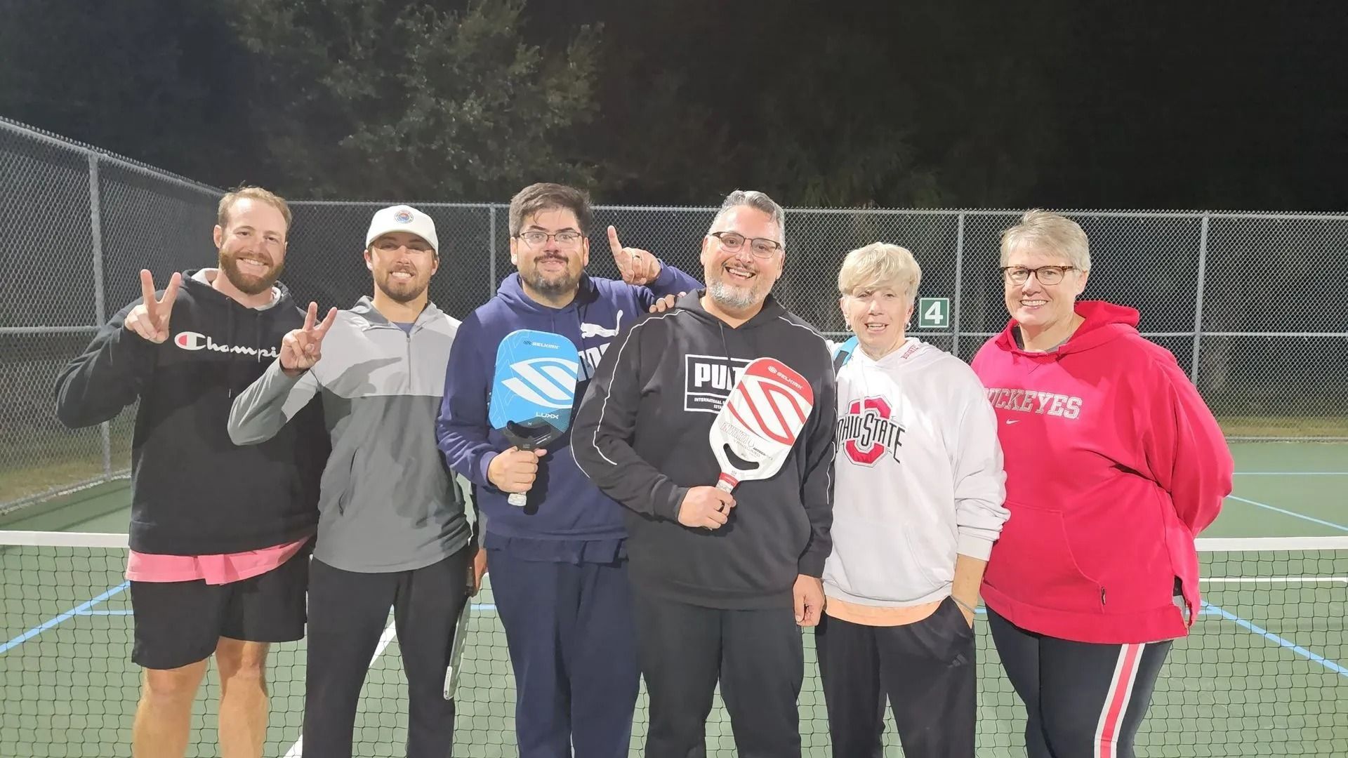 A group of people are posing for a picture on a tennis court.