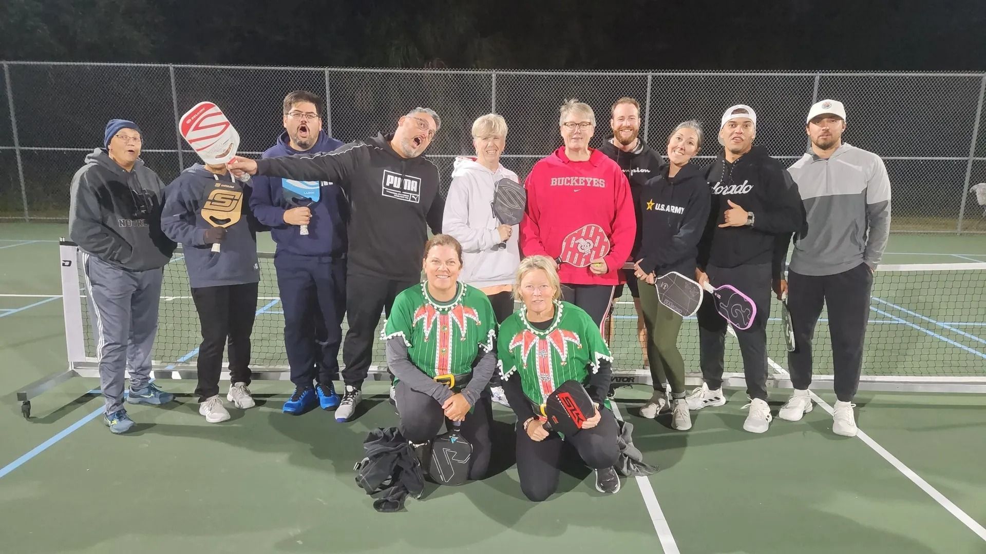 A group of people are posing for a picture on a tennis court.