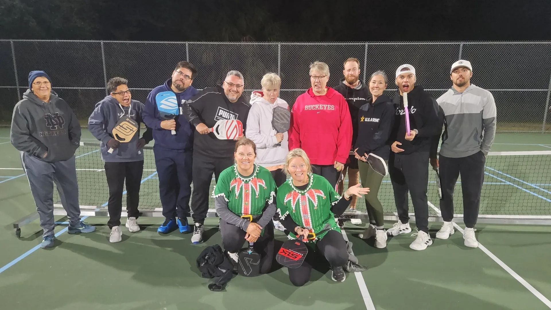 A group of people are posing for a picture on a tennis court.