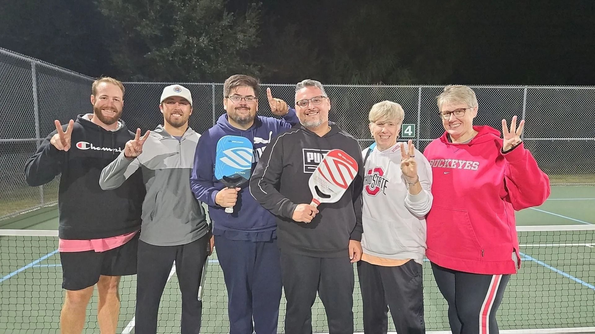 A group of people are posing for a picture on a tennis court.
