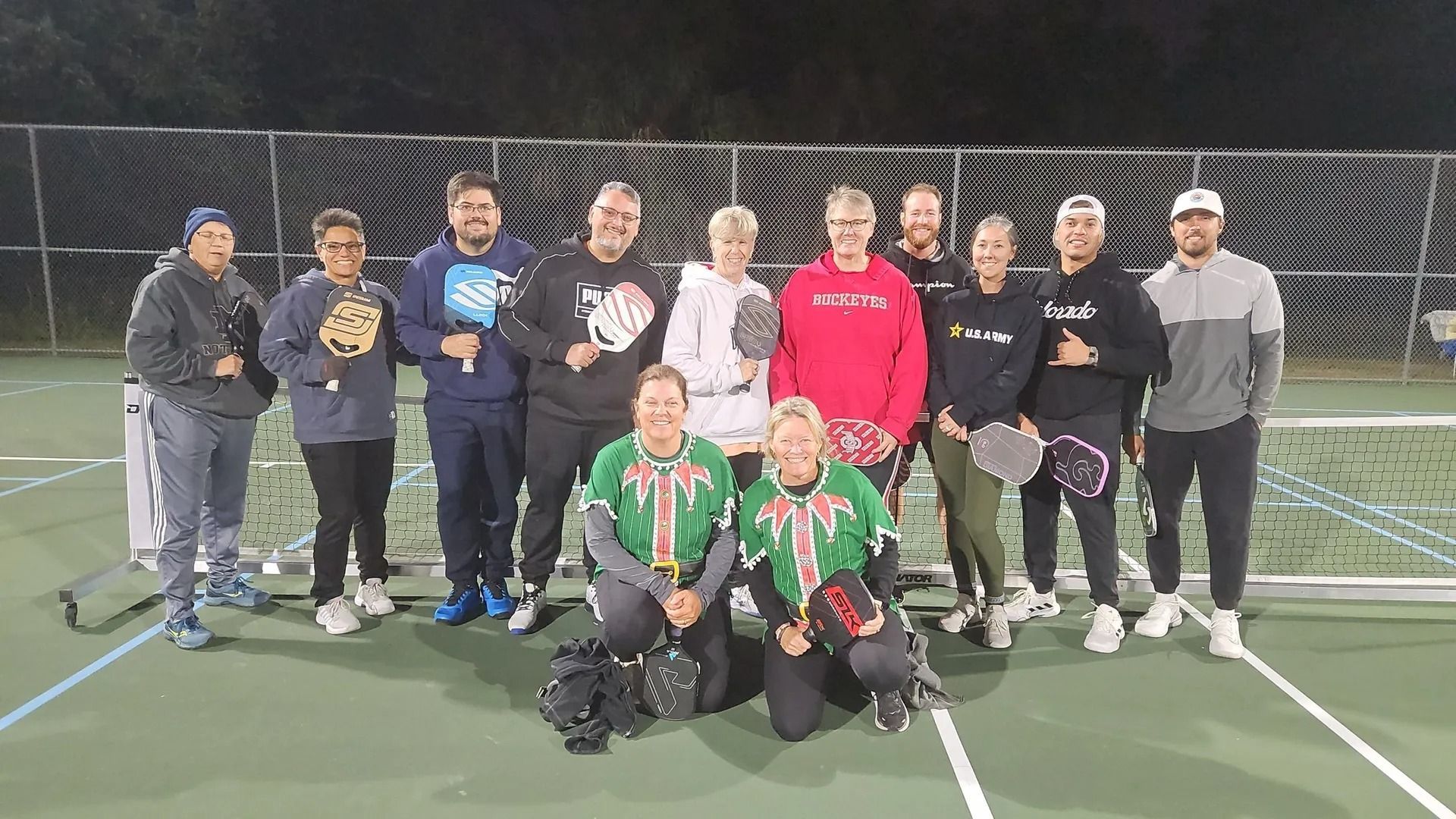 A group of people are posing for a picture on a tennis court.