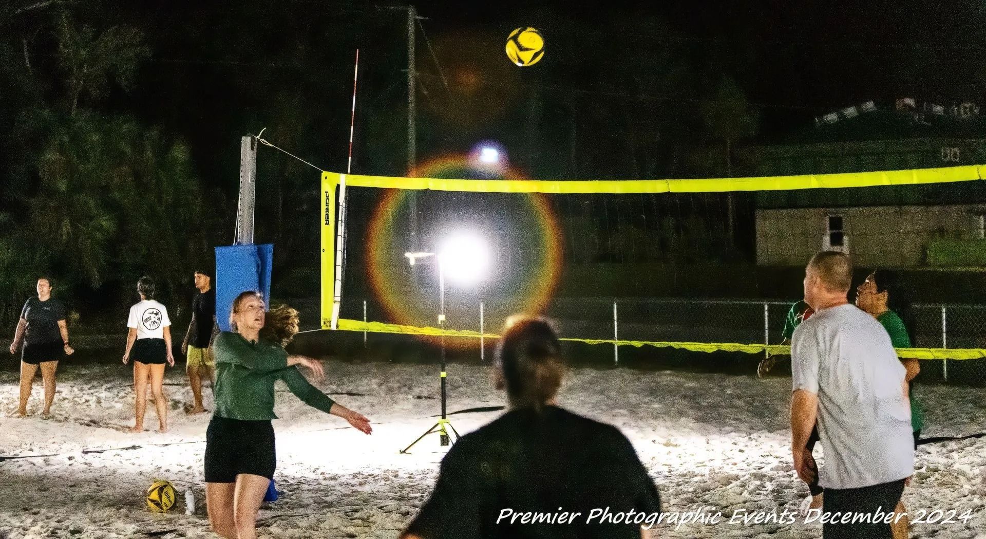 A group of people are playing volleyball on a beach at night.