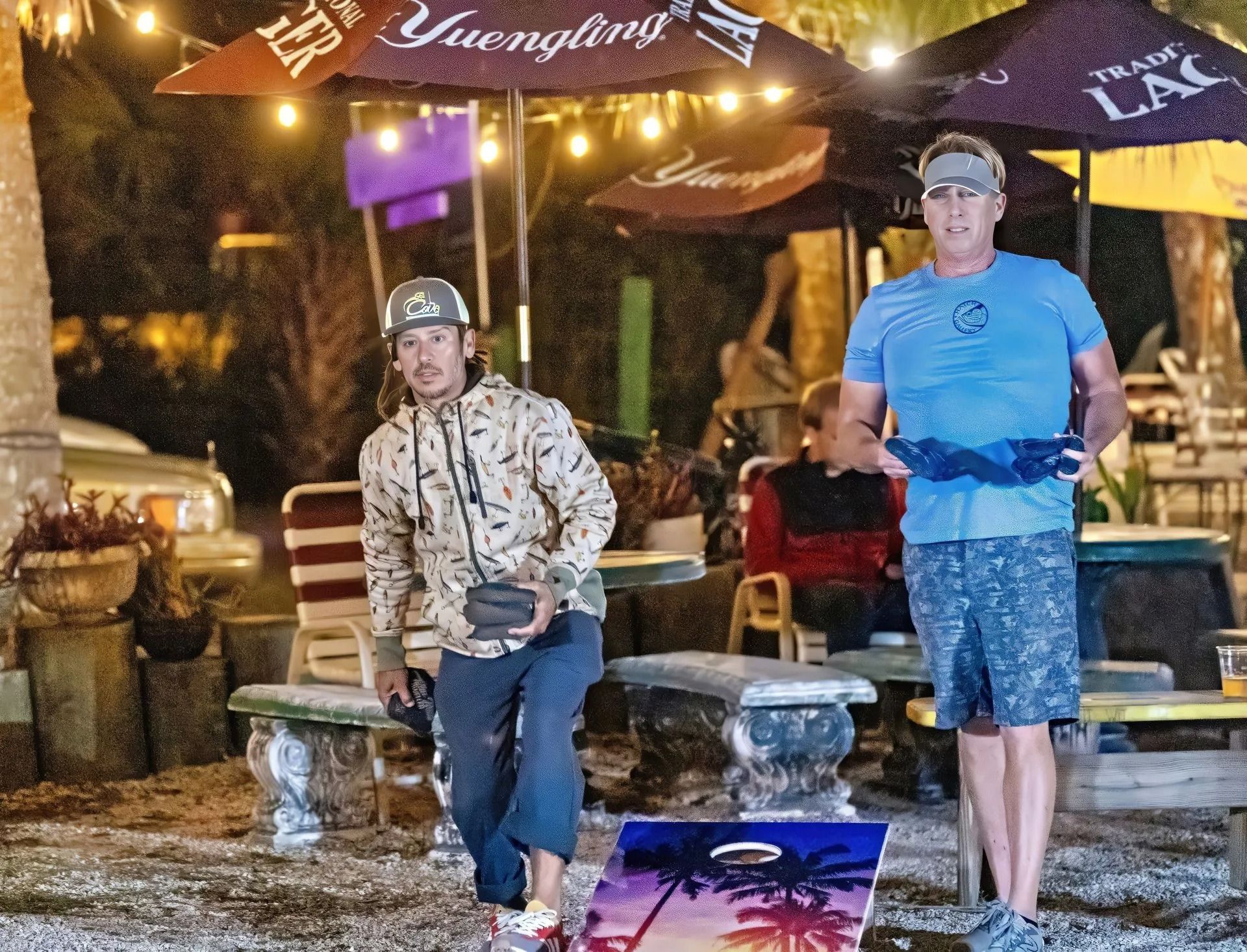 Two men are playing a game of bean bag toss at a restaurant.