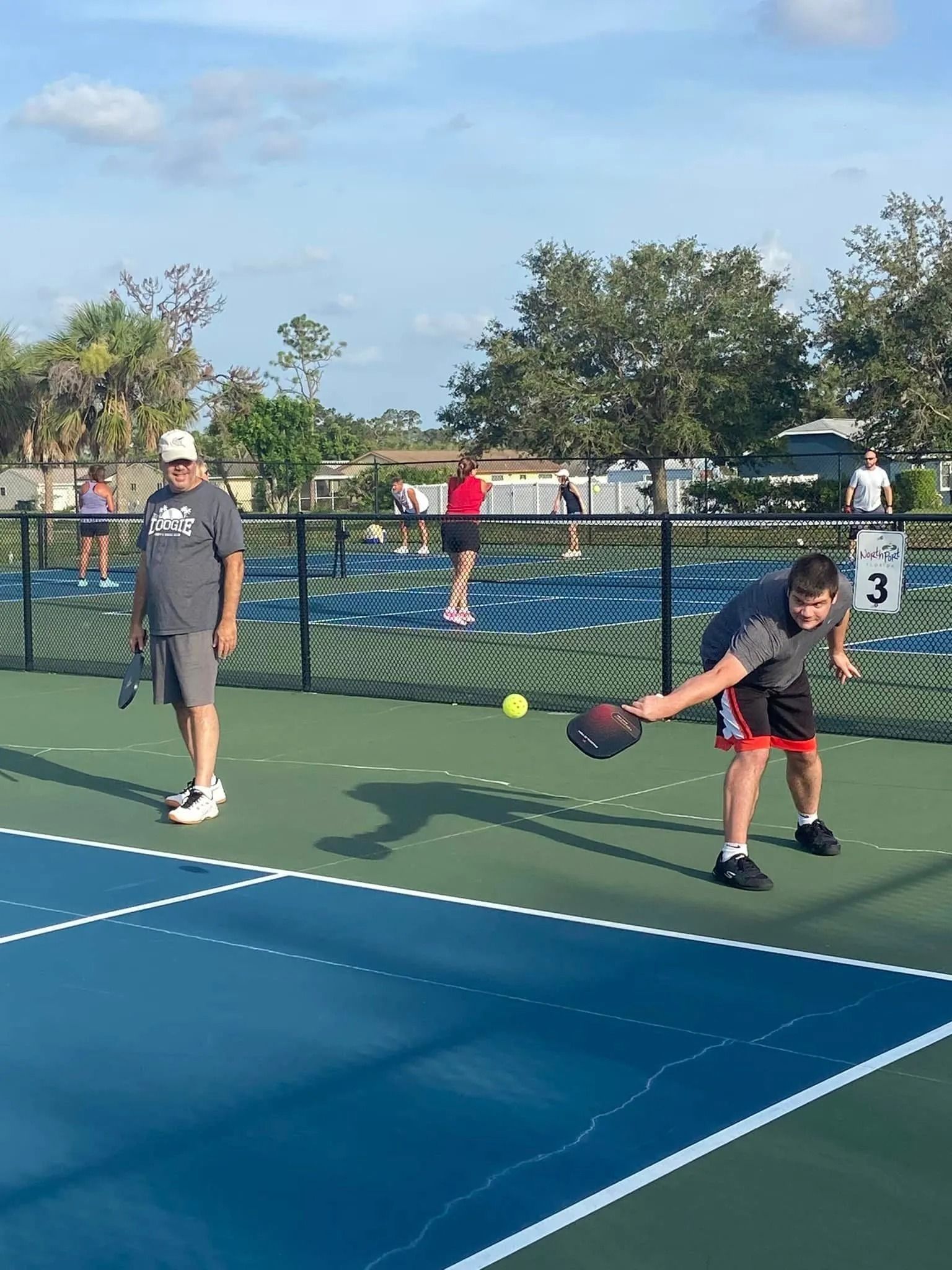 A group of people are playing tennis on a tennis court.