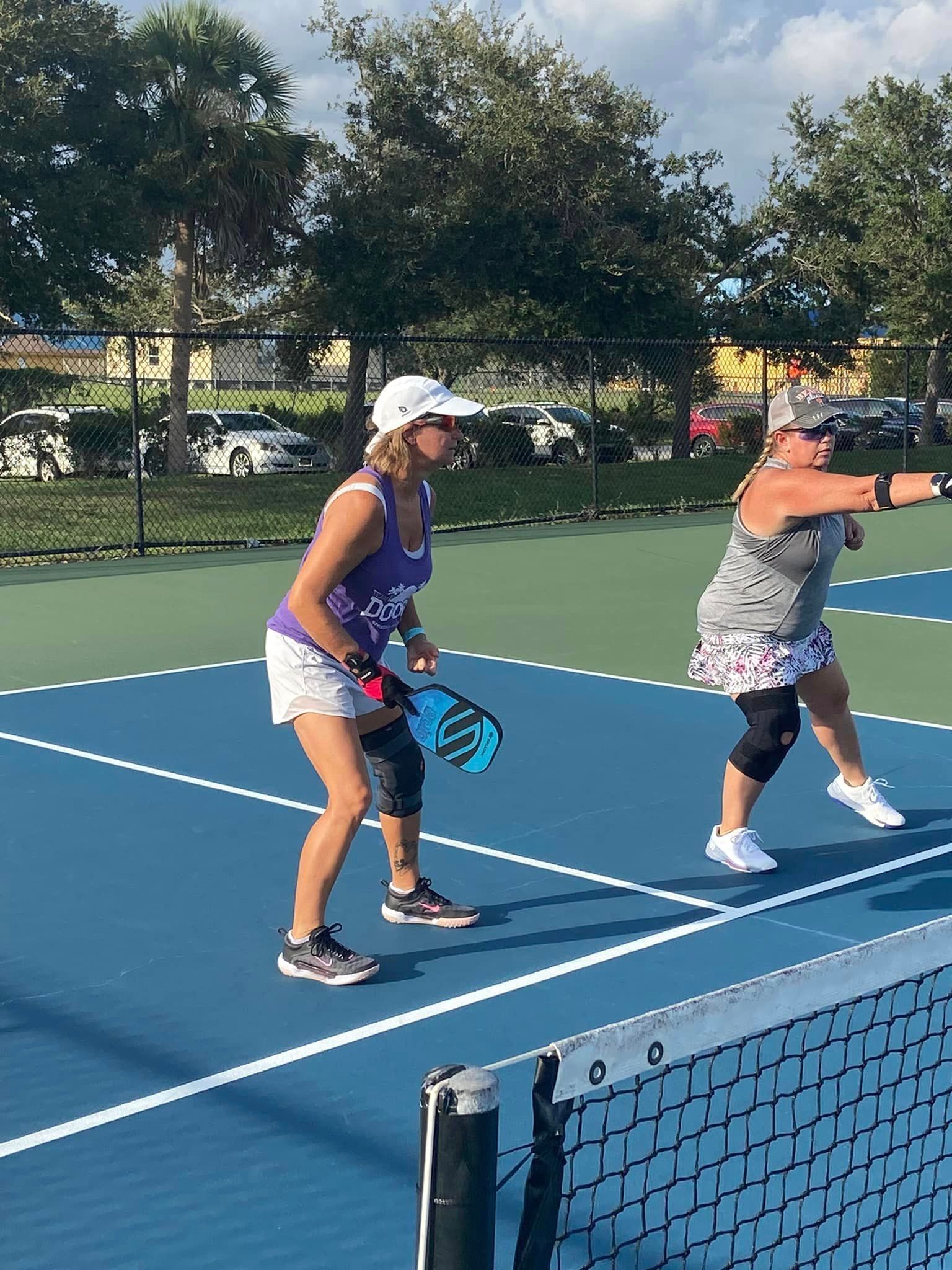 Two women are playing tennis on a tennis court.