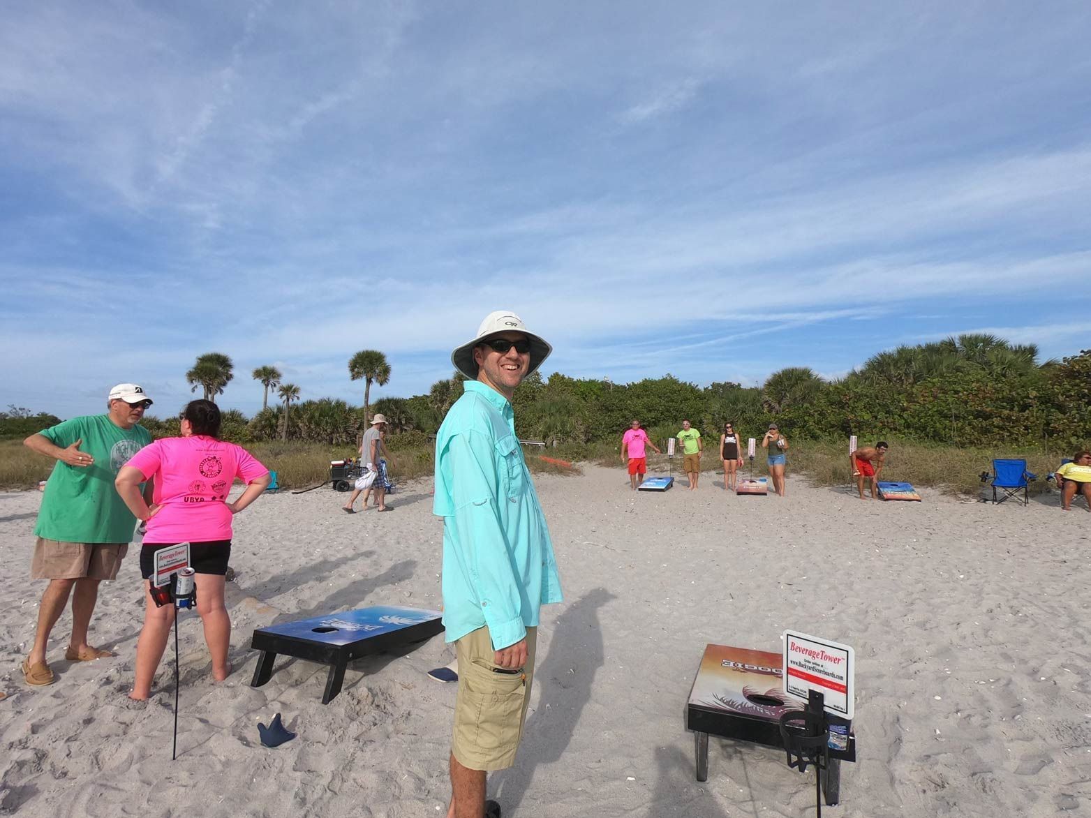 A group of people are playing a game of cornhole on the beach.