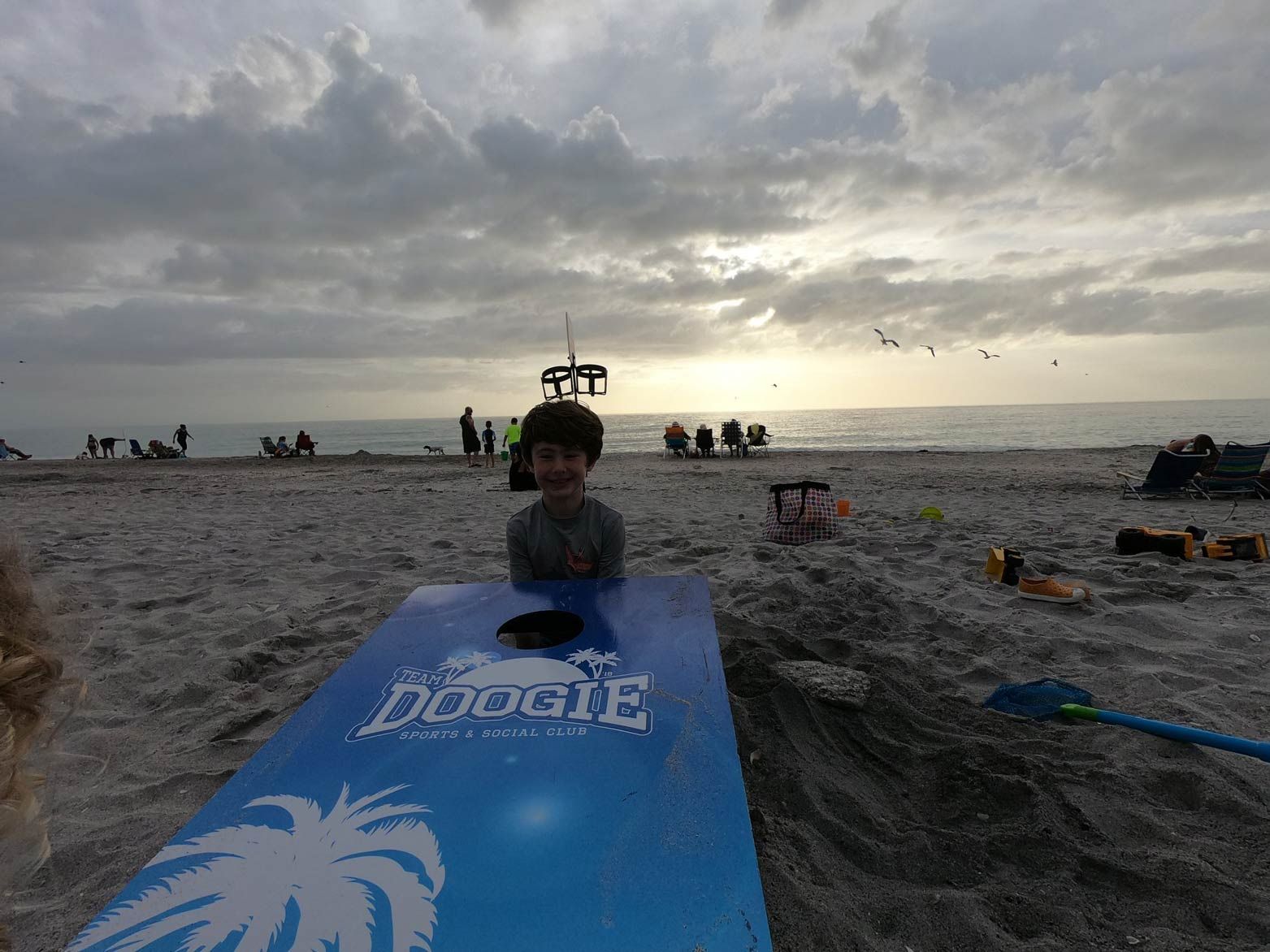 A young boy is sitting on a boogie board on the beach.