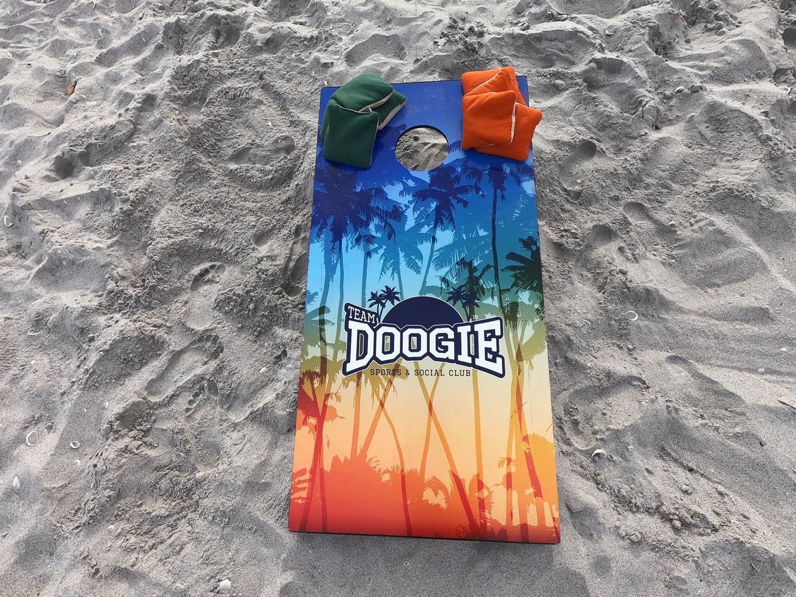 A colorful towel with the word doogie on it is sitting on a sandy beach.