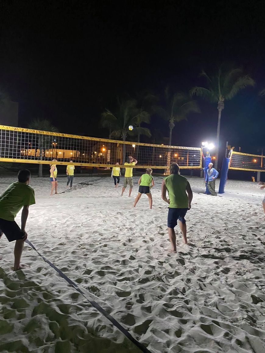 A group of people are playing volleyball on a beach at night