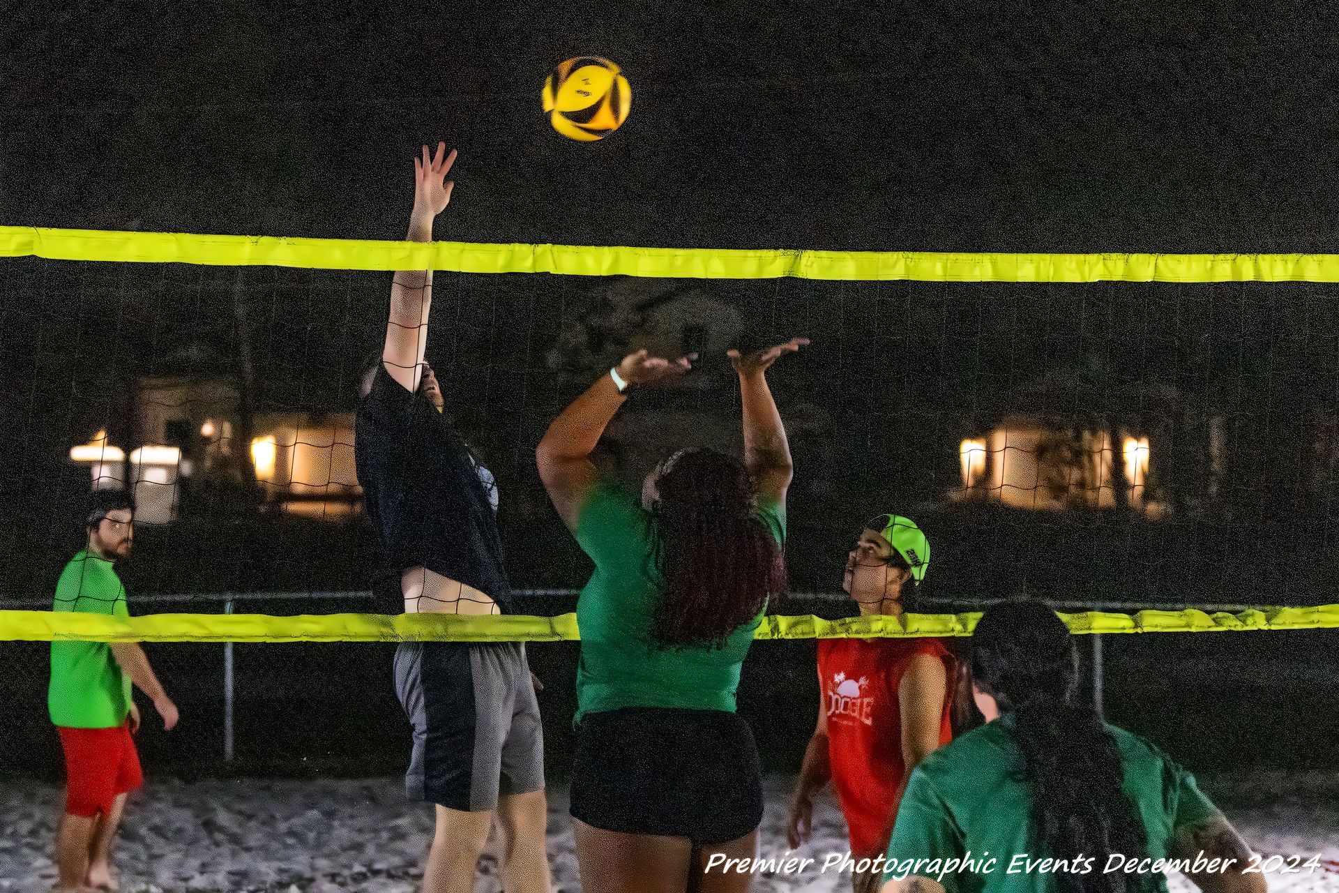 A group of people are playing volleyball on a beach at night.
