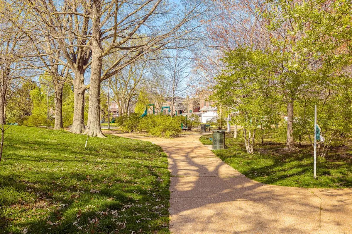 A dirt path in a park surrounded by trees and grass.