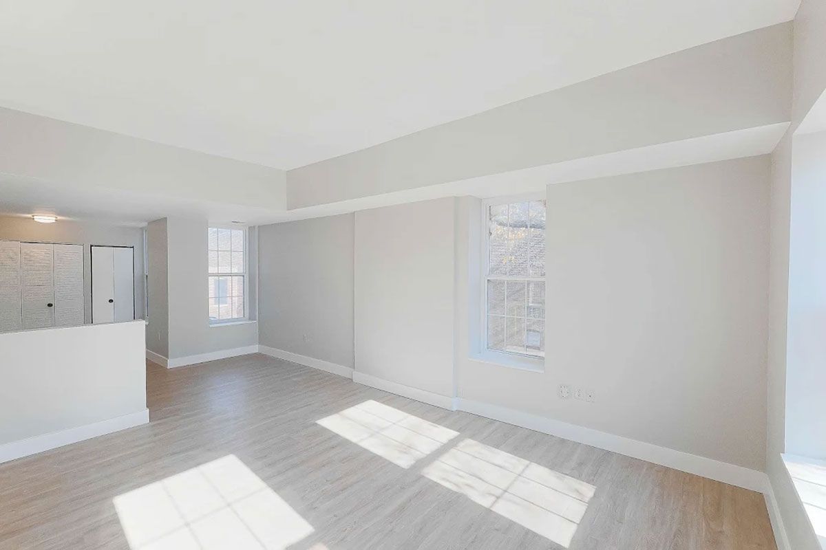An empty living room with hardwood floors and white walls.