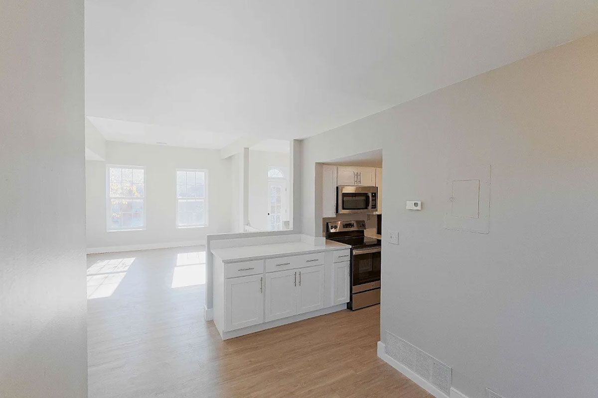 An empty apartment with a kitchen and a living room.