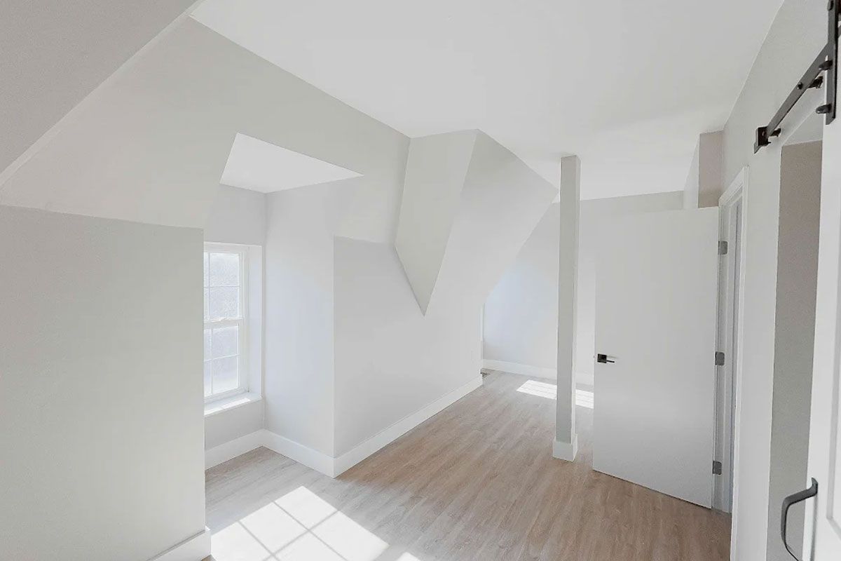 An empty room with white walls and hardwood floors.