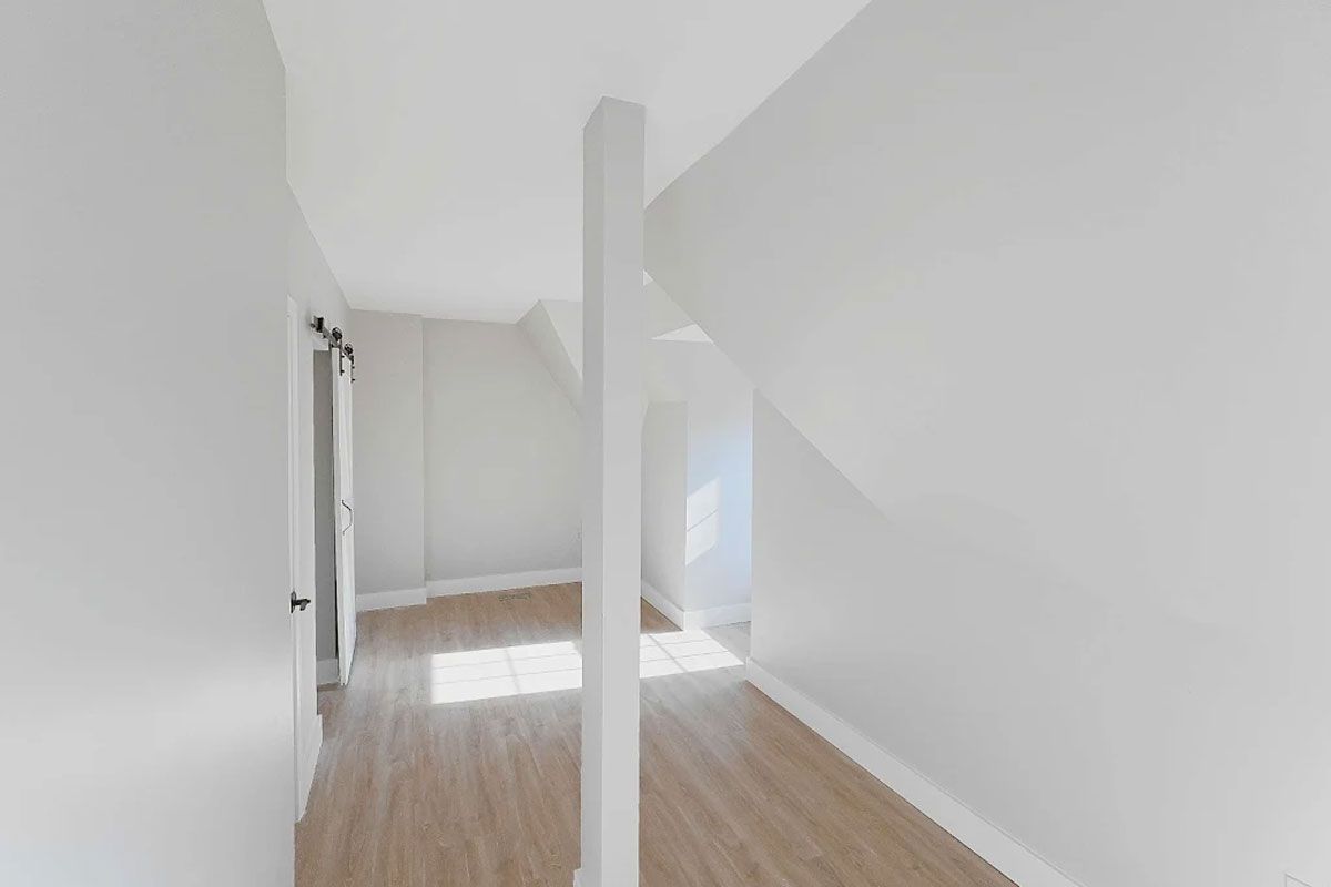 An empty room with hardwood floors and white walls.