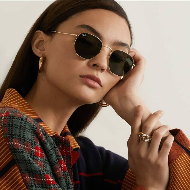 Una donna che indossa occhiali da sole Ray-Ban e una camicia a quadri