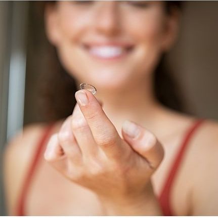 Una donna tiene in mano una lente a contatto.
